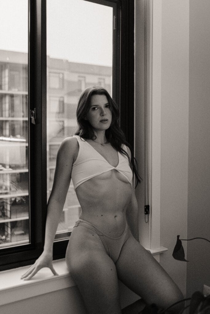 Woman in underwear leaning against apartment window - black and white photo