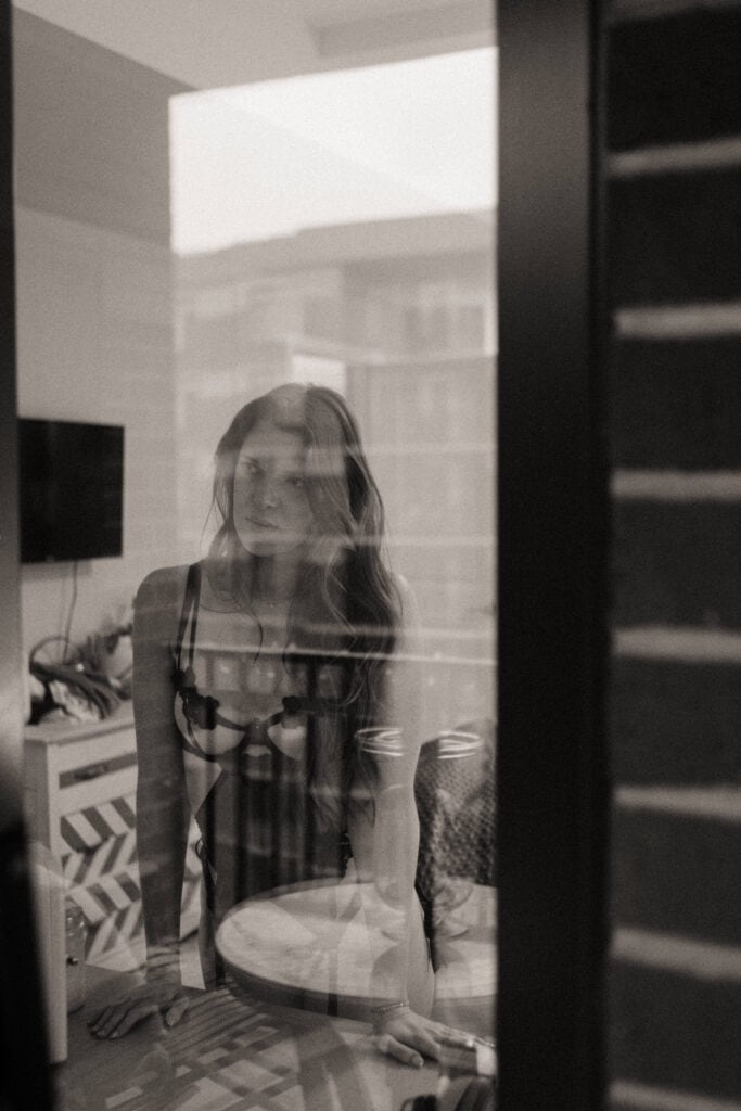 Woman seen through glass in B&W bedroom photo