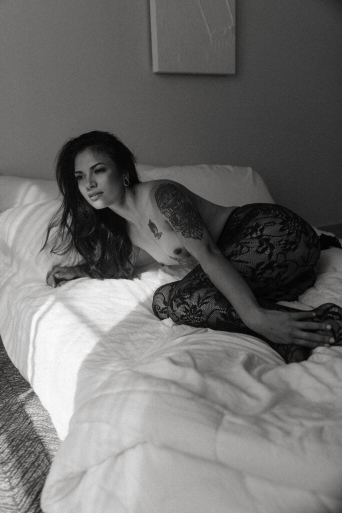 a woman posing in a bed with black lace tights on 