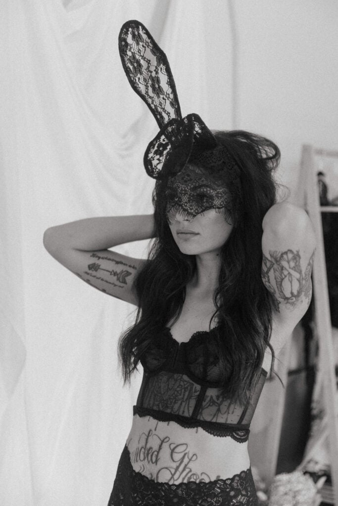 a woman putting on black lace mask and bunny ears 