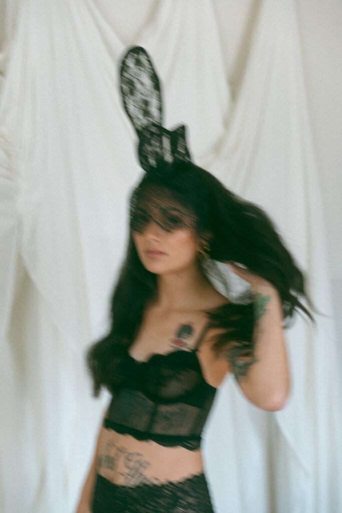 blurry photo of a woman wearing black lace face mask and bunny ears 