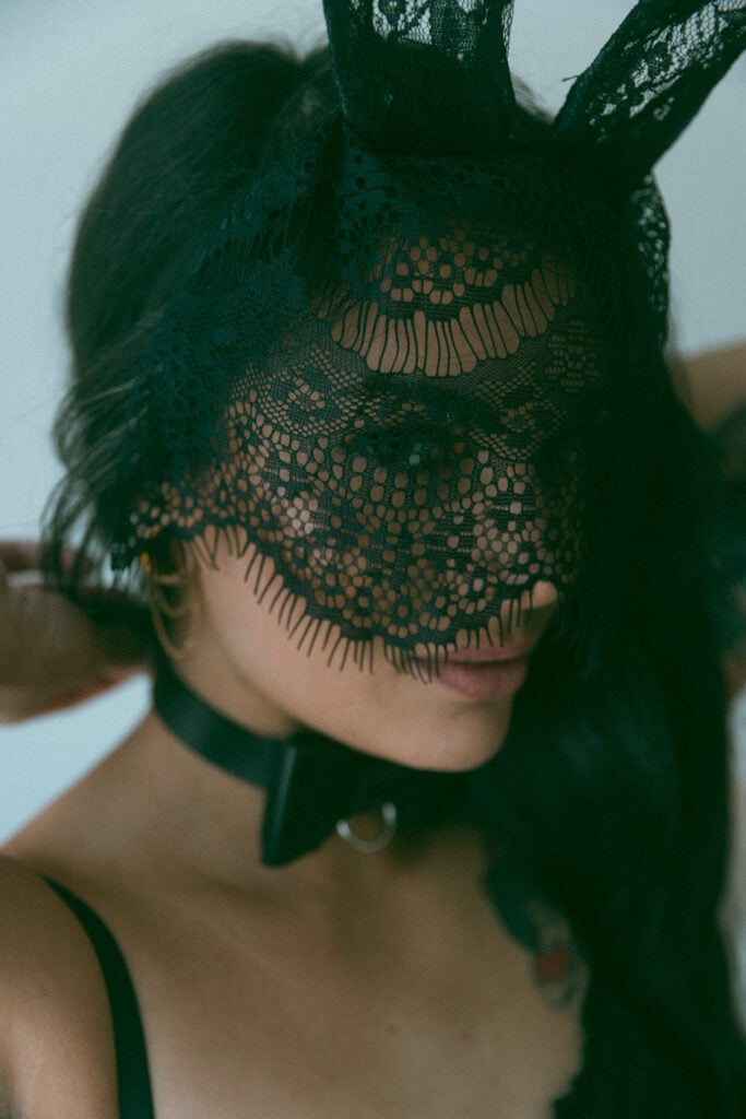 close up of a woman wearing black lace face mask and bunny ears 