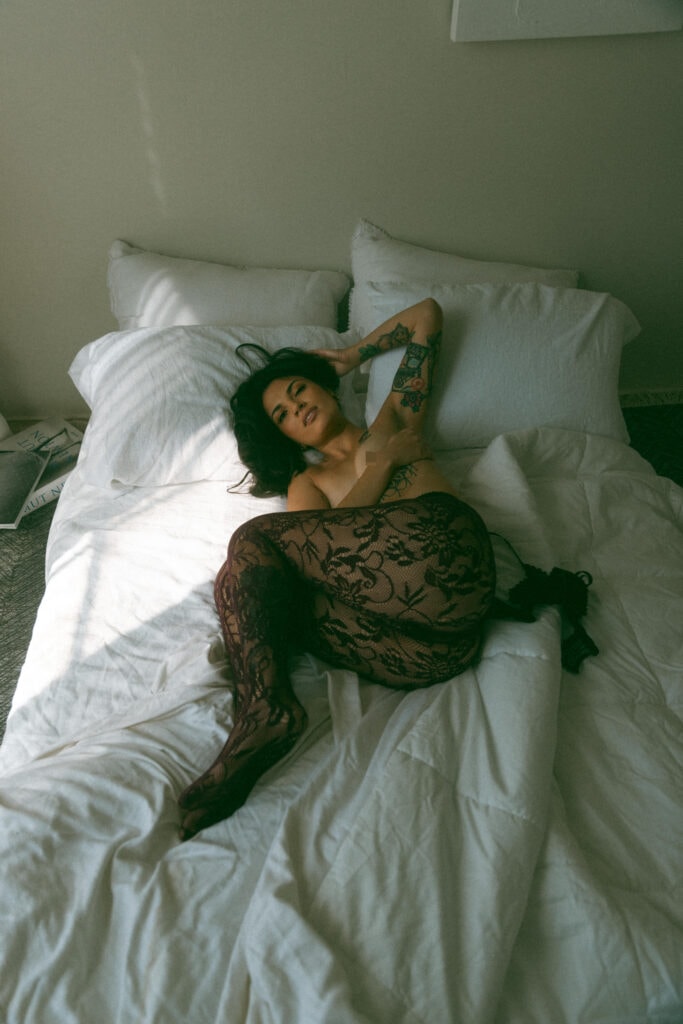 a woman in a bed. looking at the camera with black lace tights on 