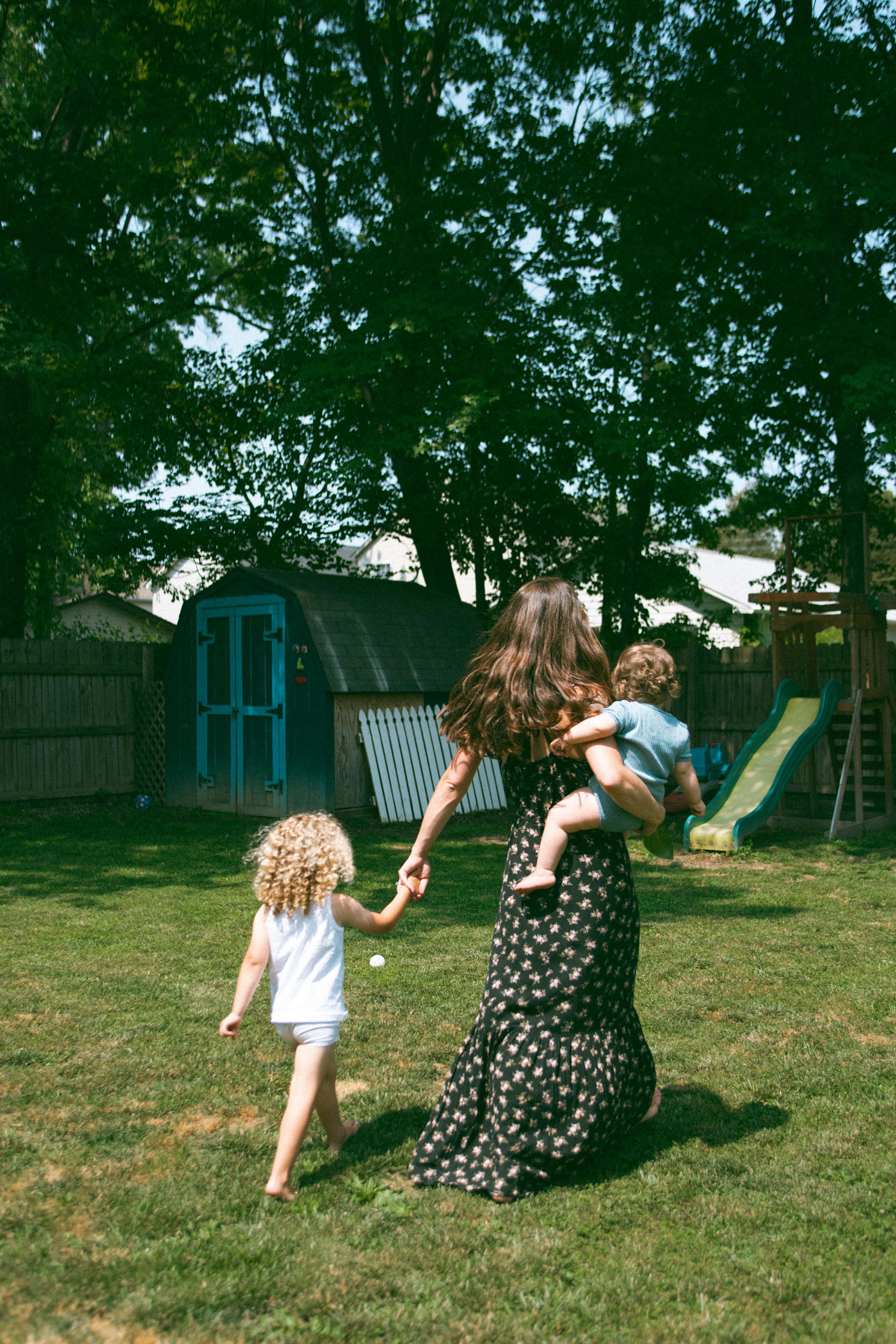 mother and kids walking toward the swings in their backyard