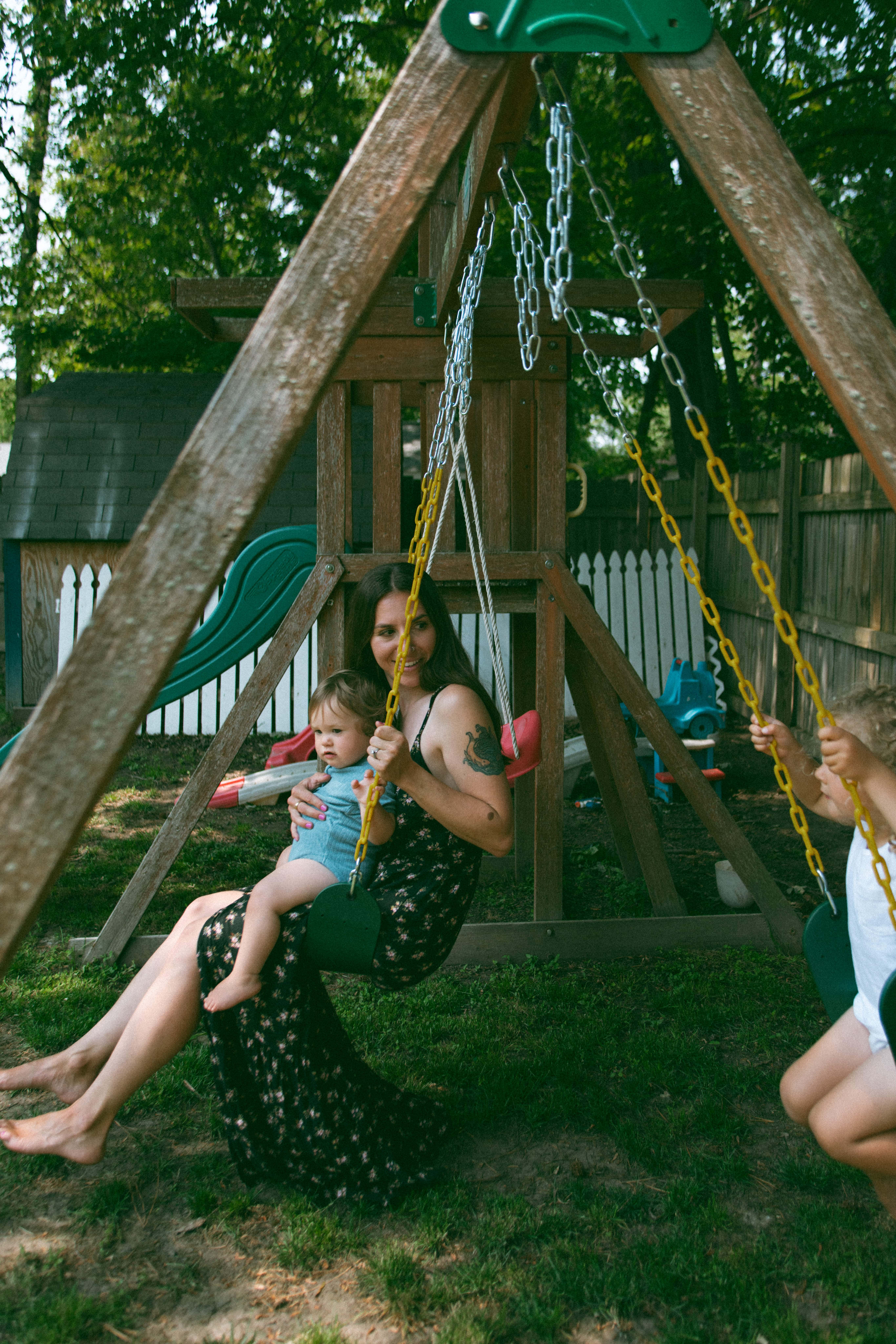 mother with children swinging on their swing set during motherhood photoshoot 