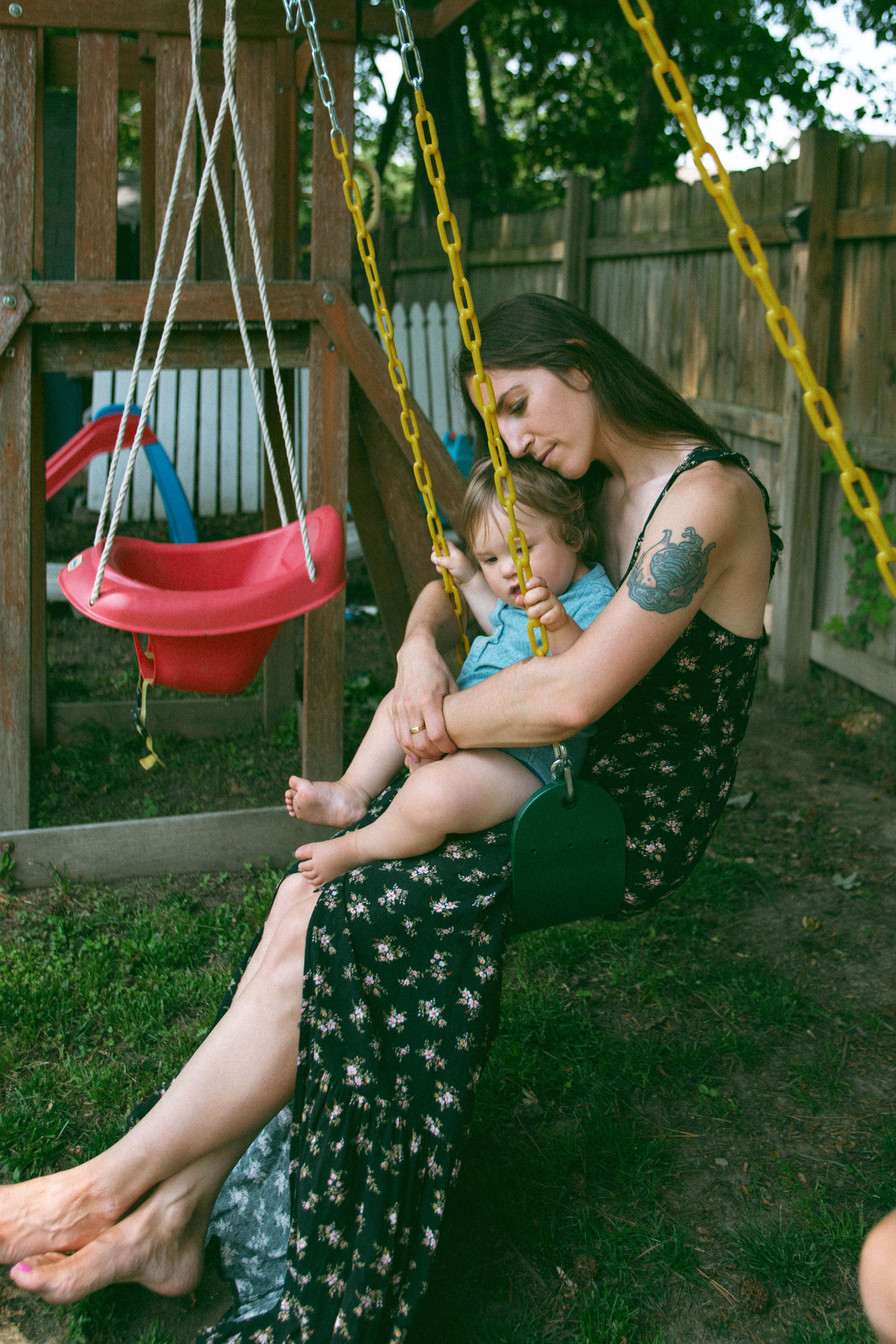 mother cuddling daughter on the swings during motherhood photoshoot 