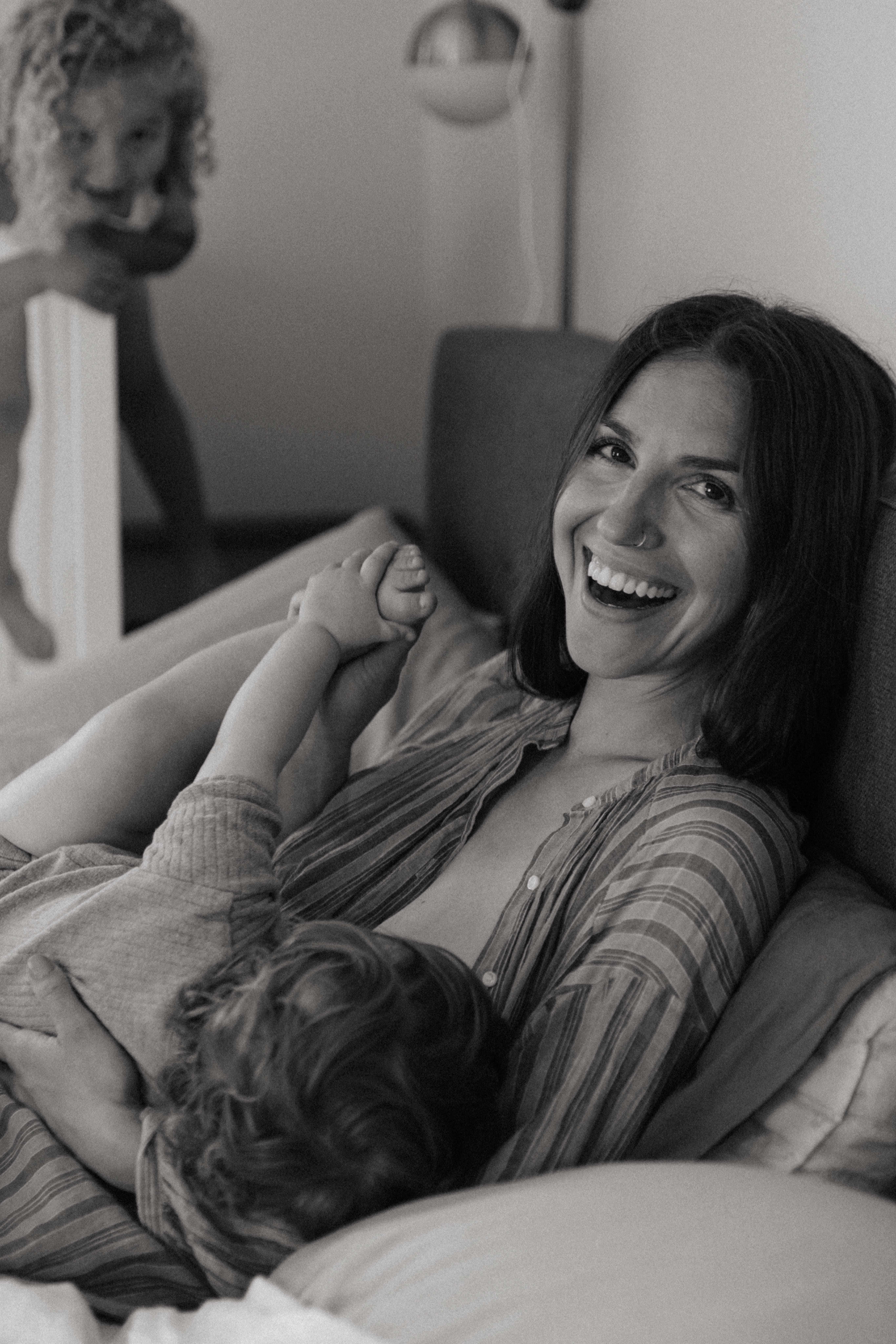 mother smiling while breastfeeding during motherhood photoshoot