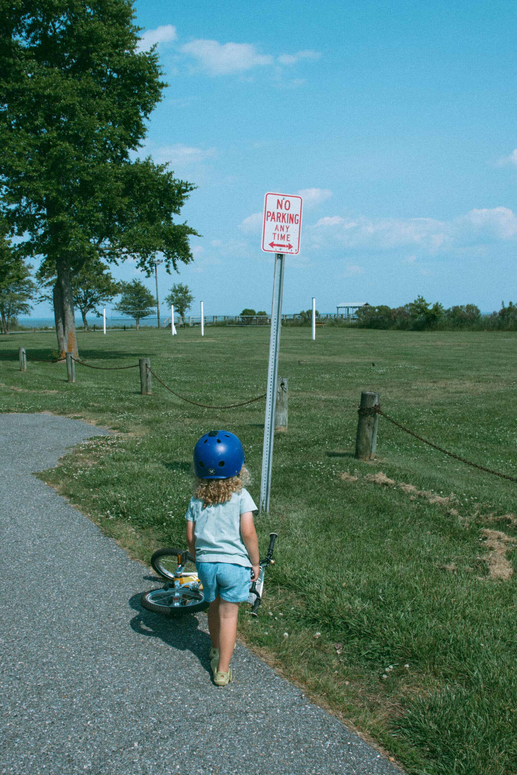 son looking at a sign with his bike helmet on 