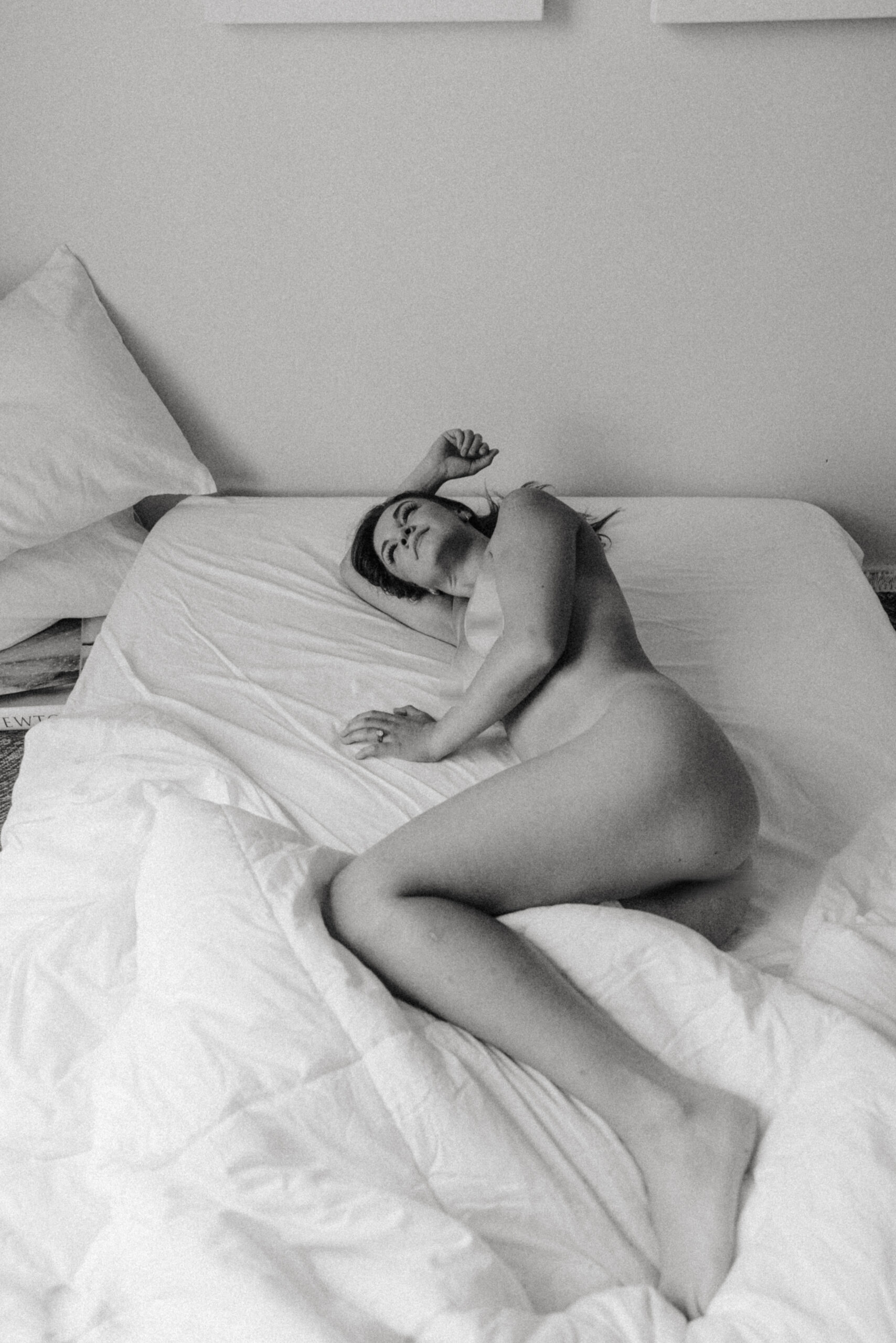 intimate portraiture of a nude woman laying in a bed 