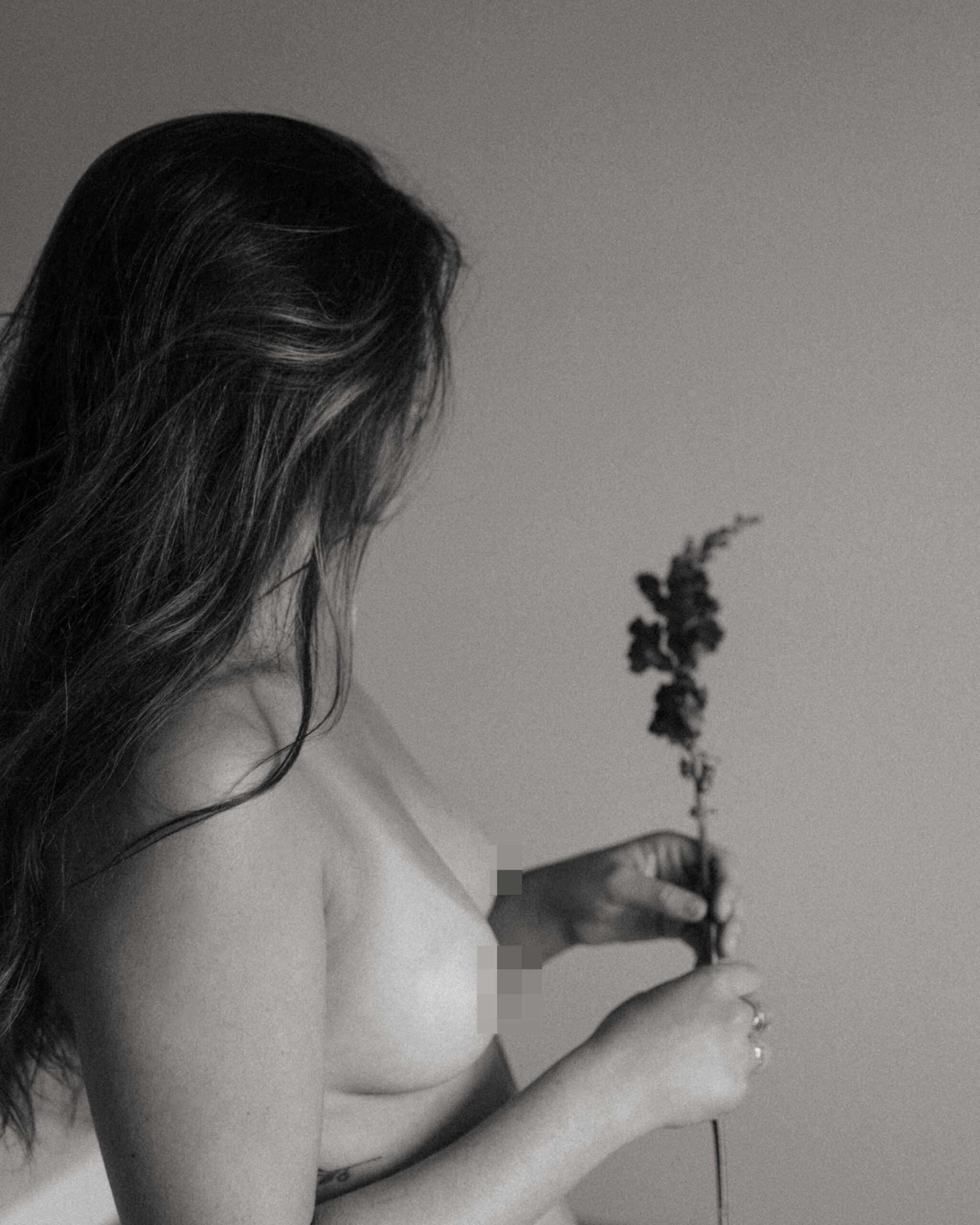 side profile of a topless woman holding a flower