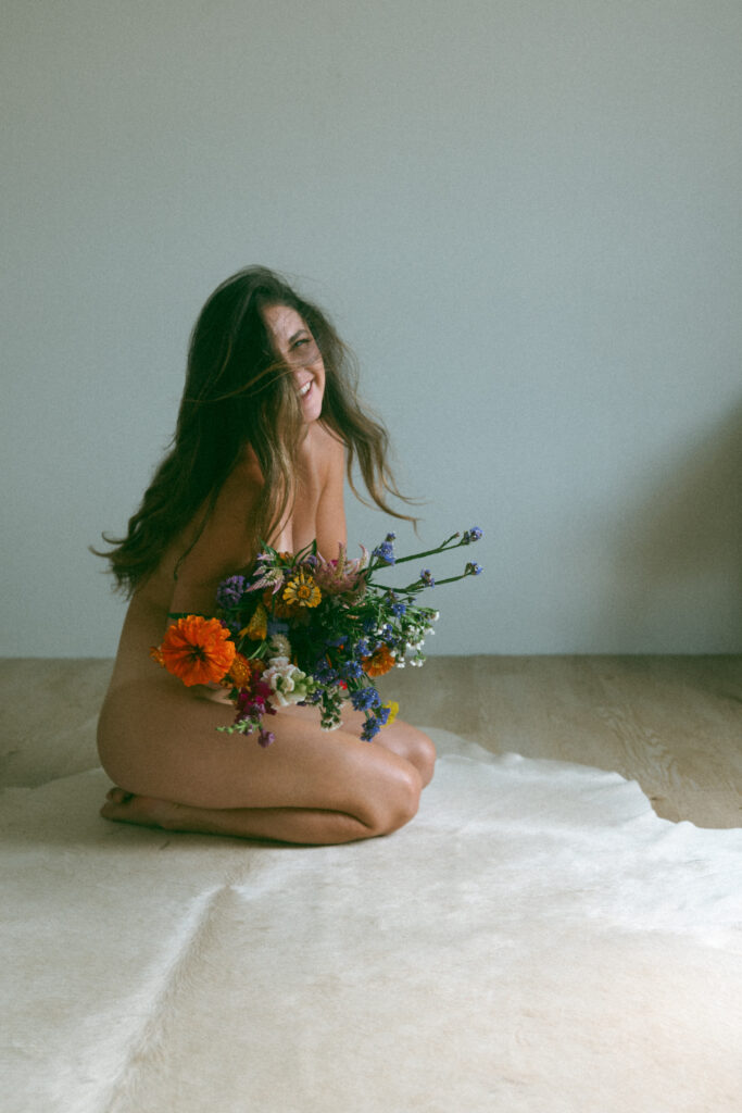 a woman holding a bouquet of flowers at a boudoir session