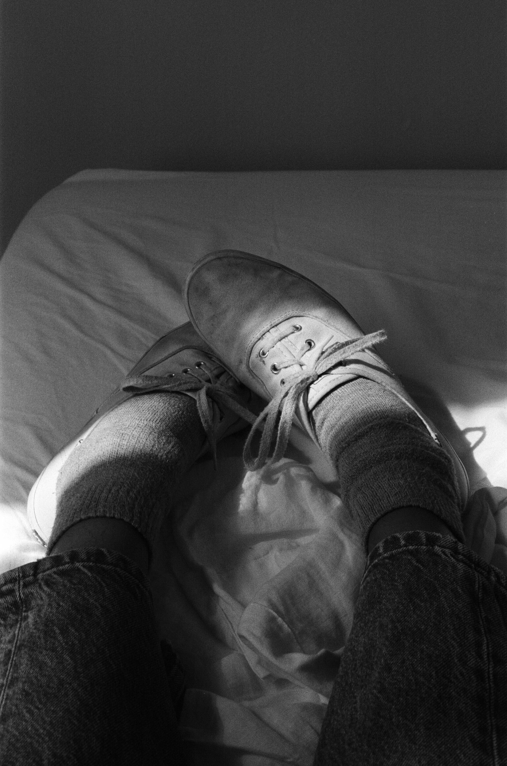 a black and white photo of shoes on a bed with light and shadows on them 