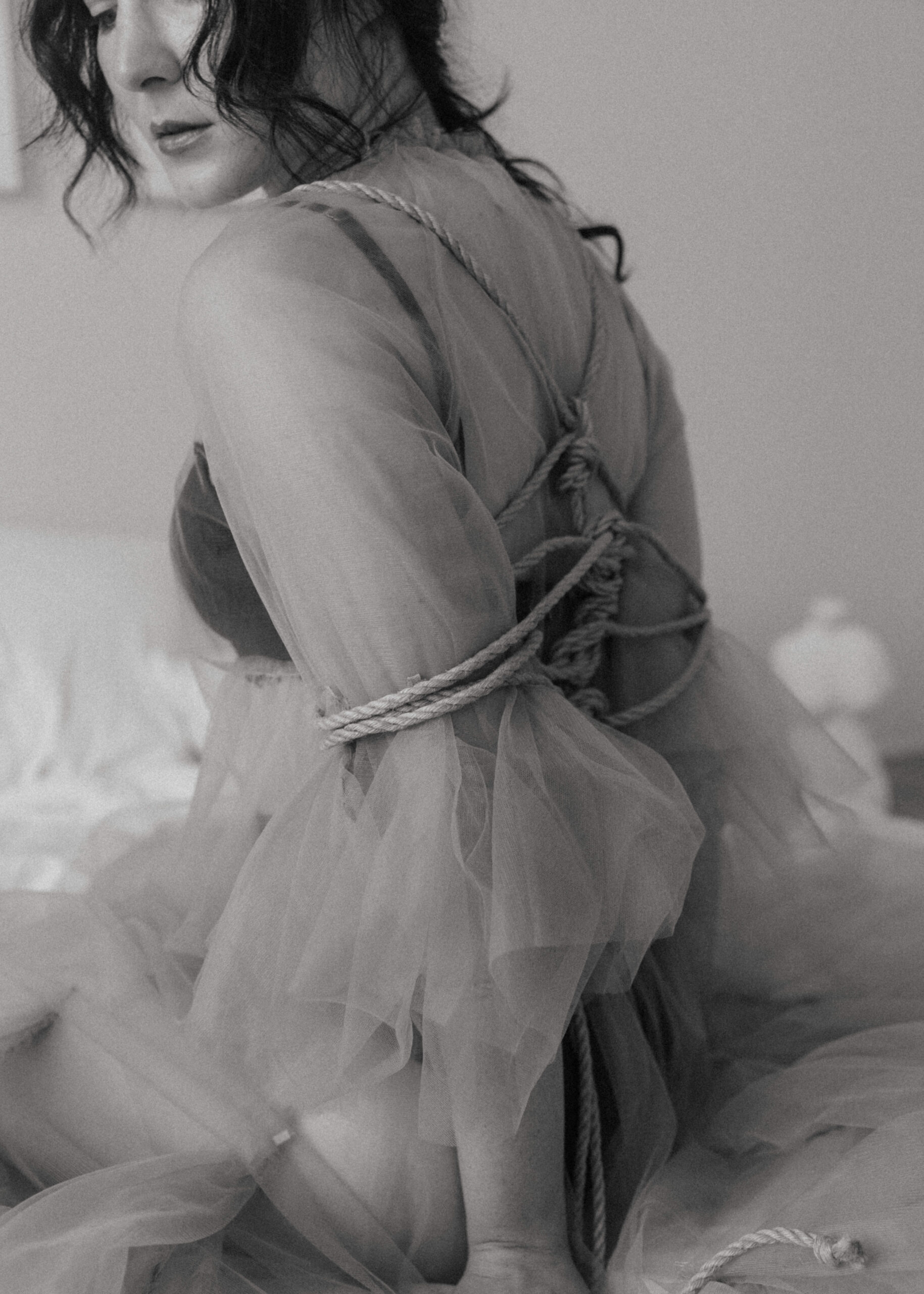 woman in a sheer dress with her arms and back tied up 