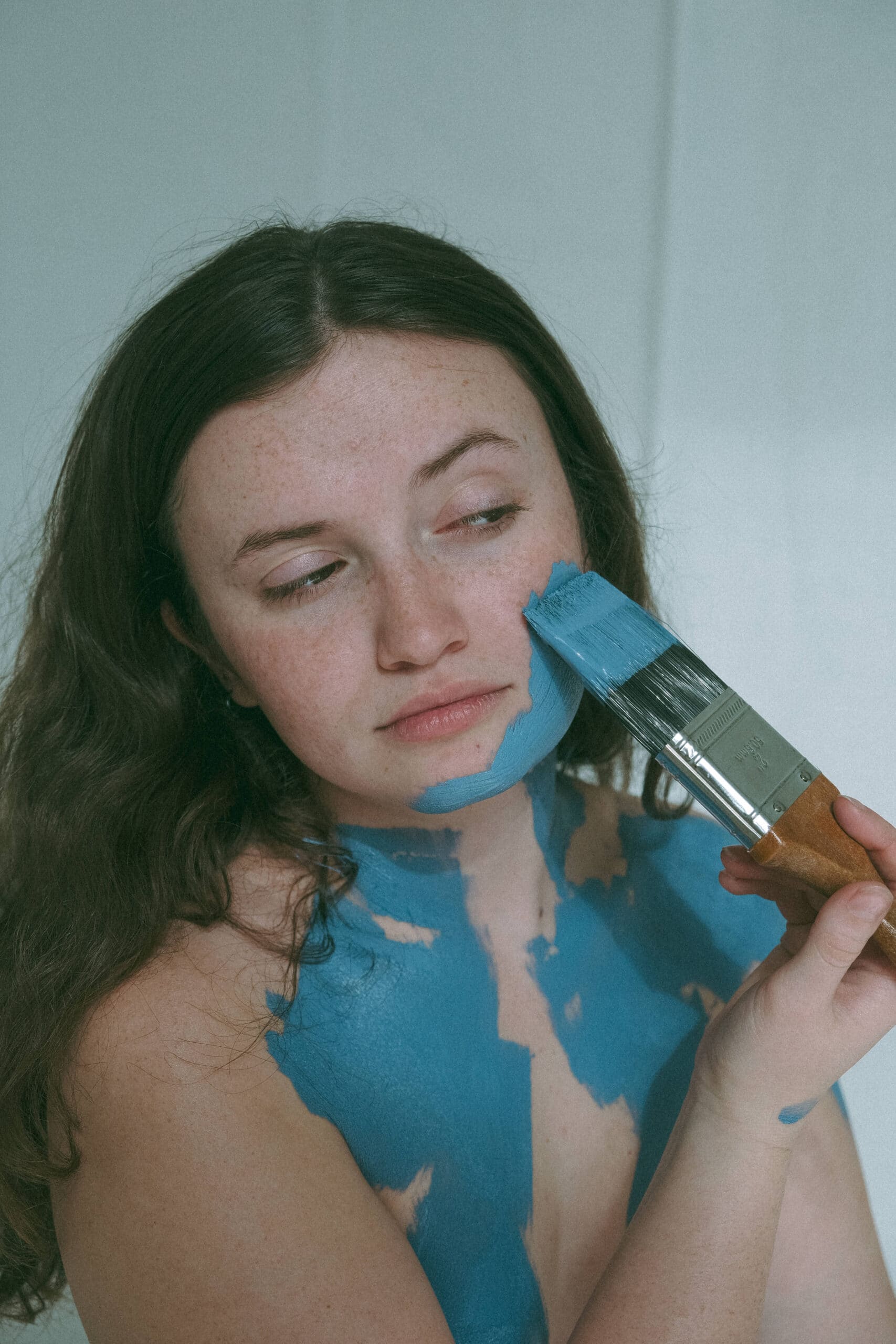 a woman painting blue paint on her face 