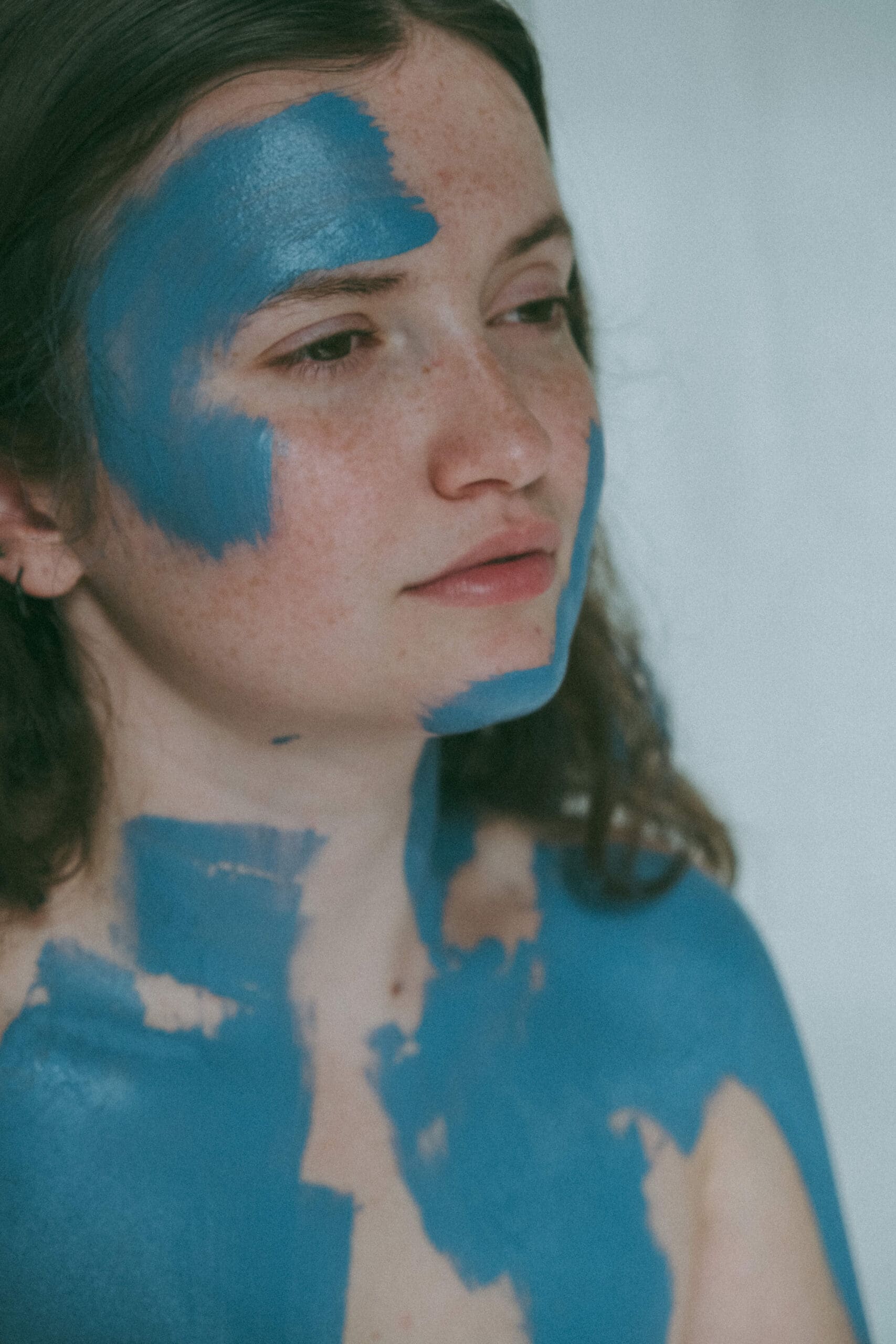a close up of a model with blue paint on her face during a creative photoshoot