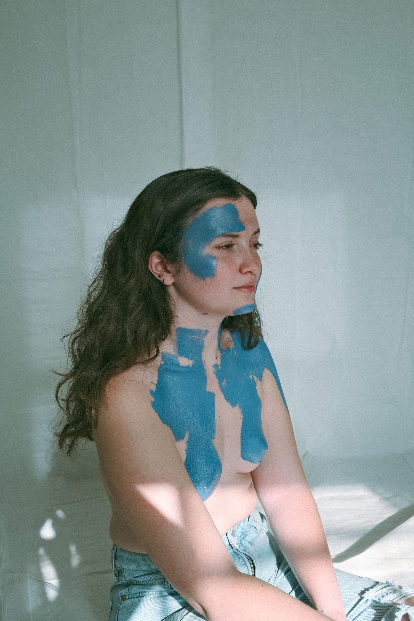 a topless, blue body painted woman facing the side 