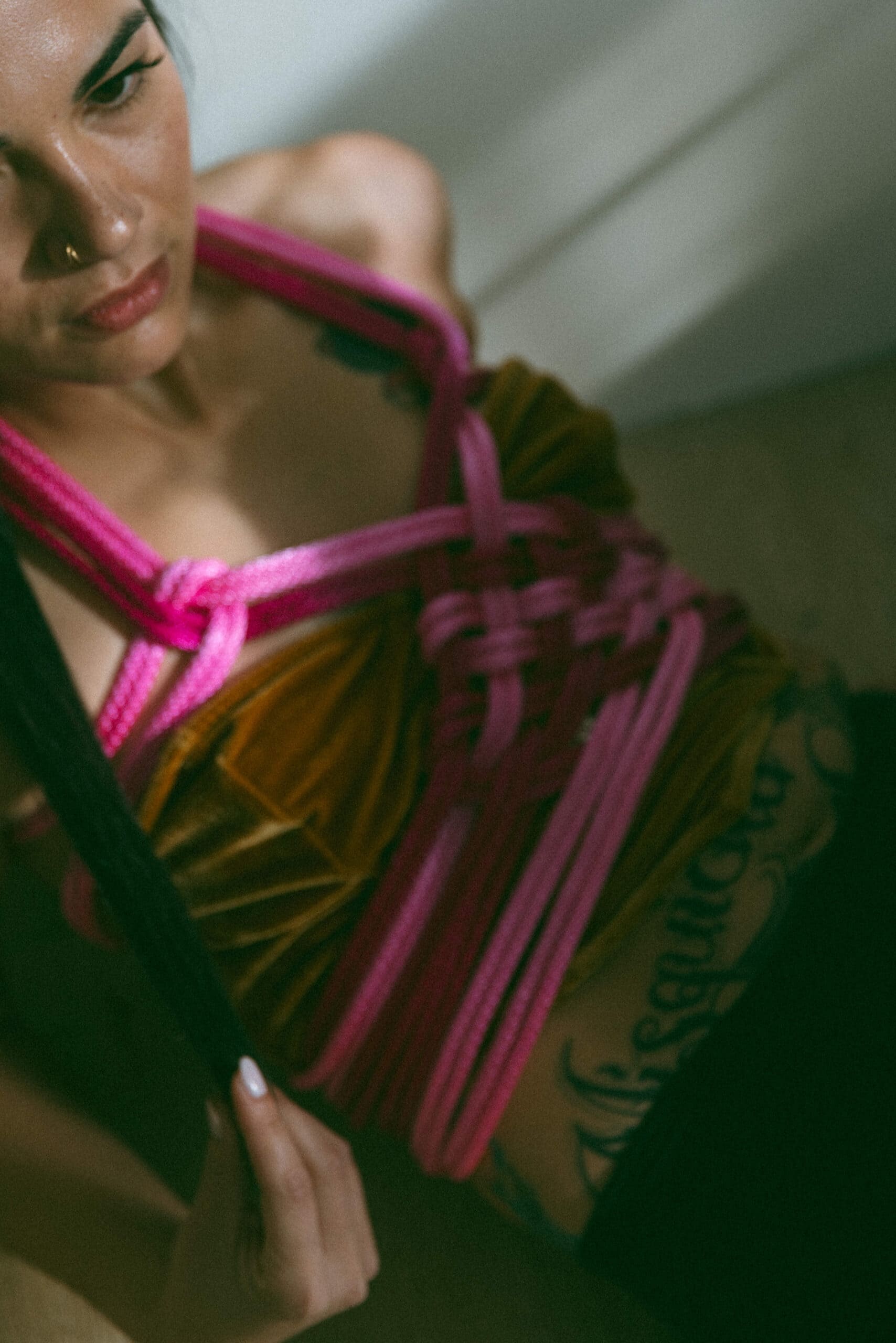 an artistic view of a woman with pink ropes tied around her torso