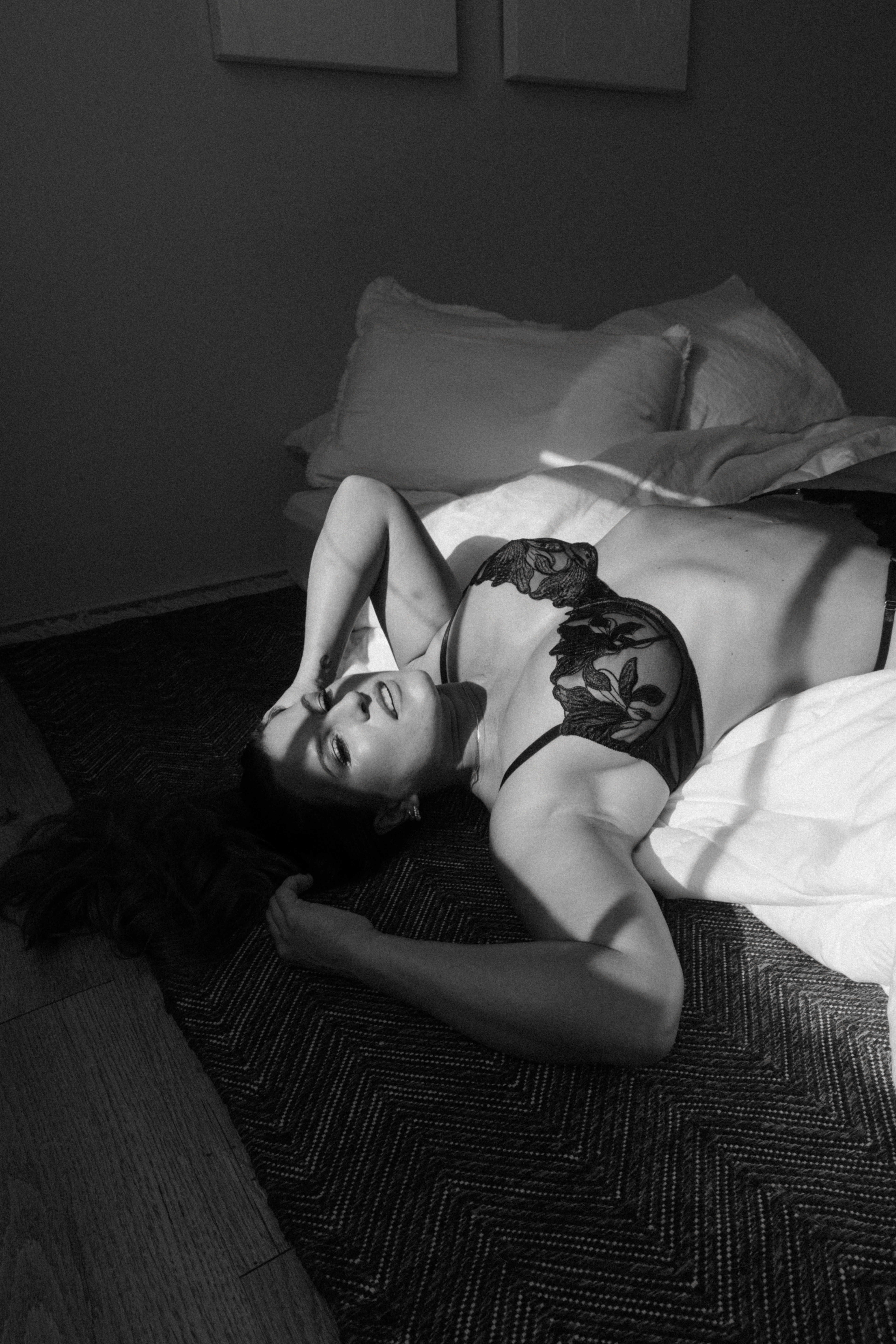 black and white of a woman half on the bed and half on the floor during a Maryland boudoir session