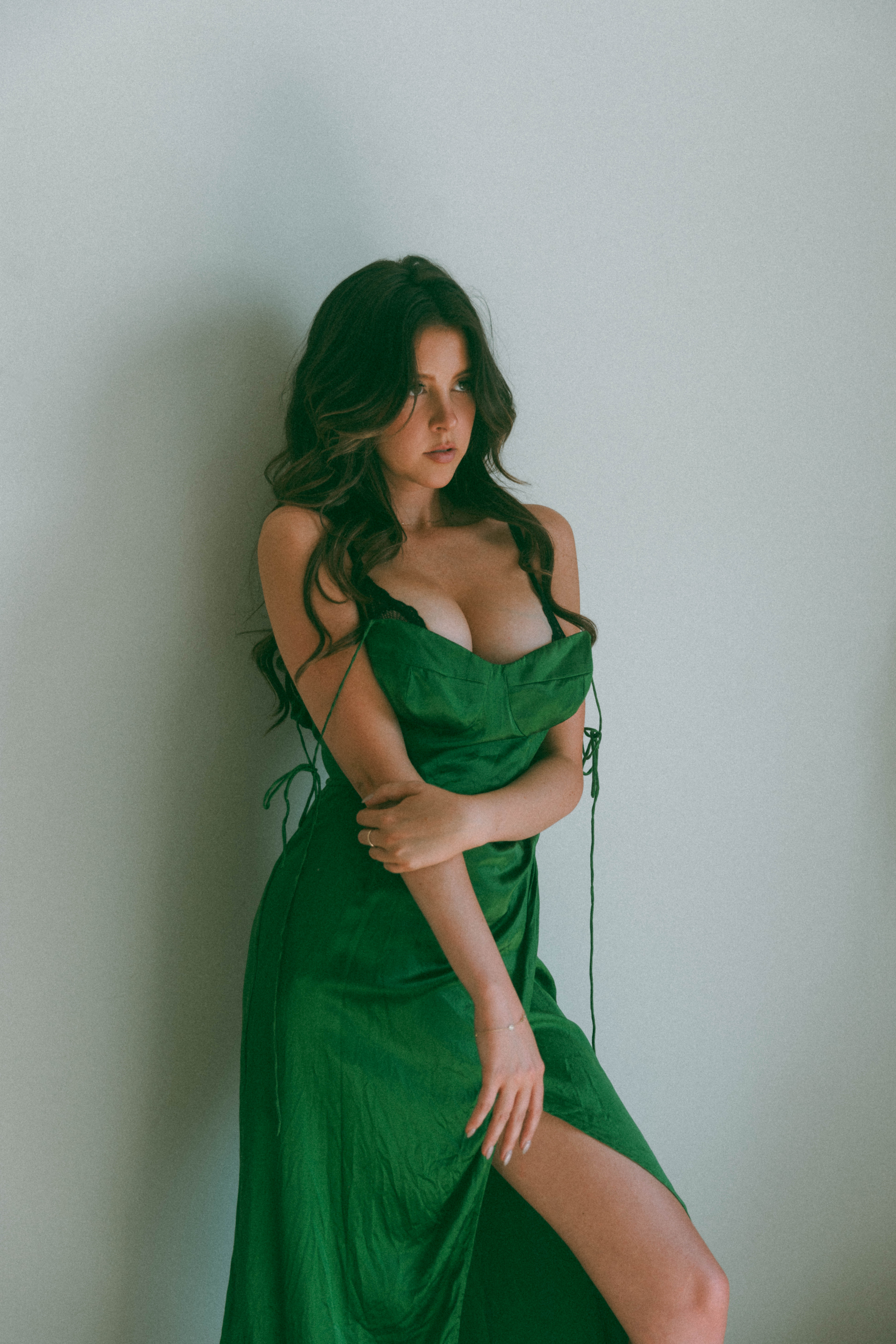 a woman standing and holding her arm while wearing a green dress during a boudoir session