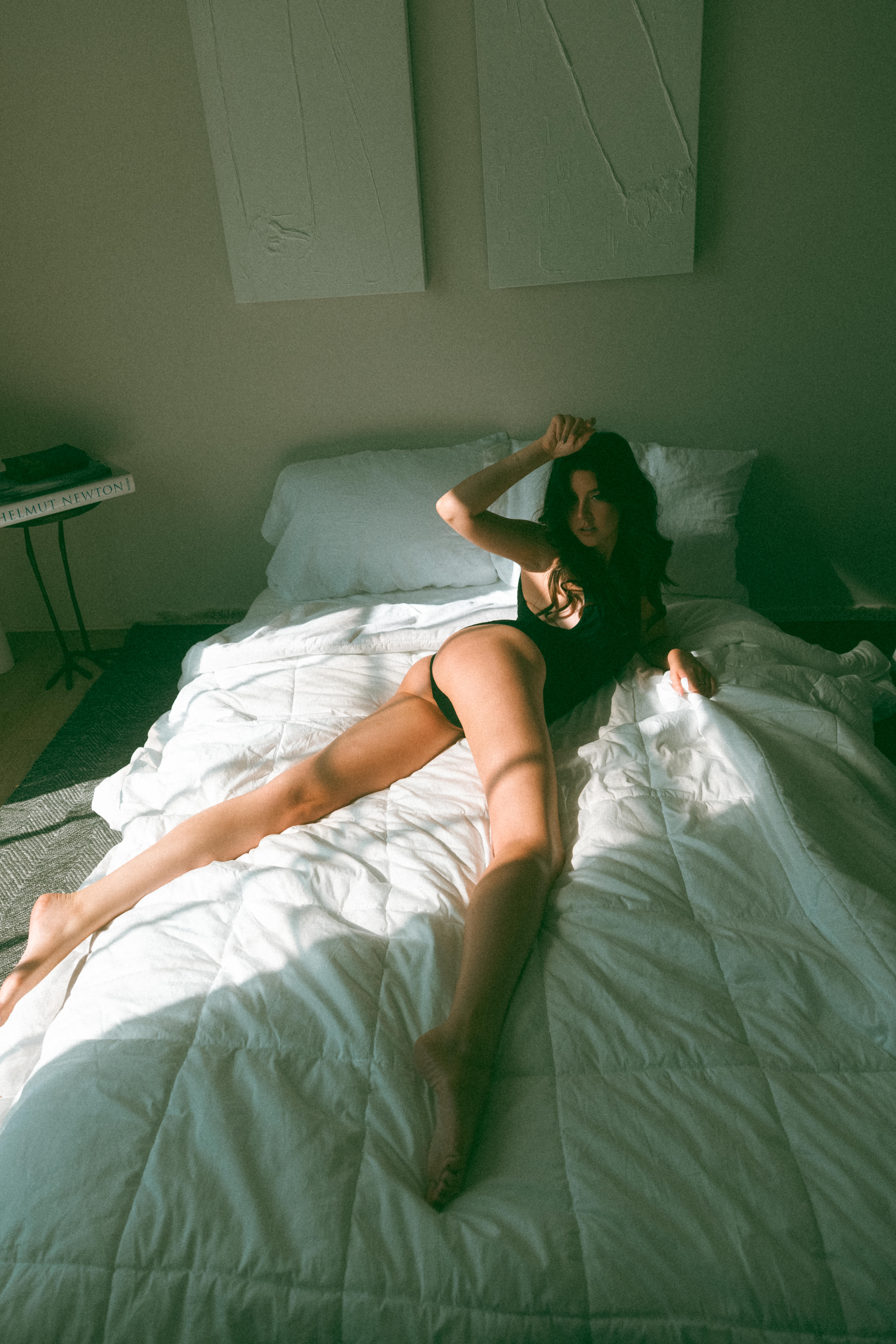 a woman laying on her stomach twisting her top half around while light shines onto her through the window