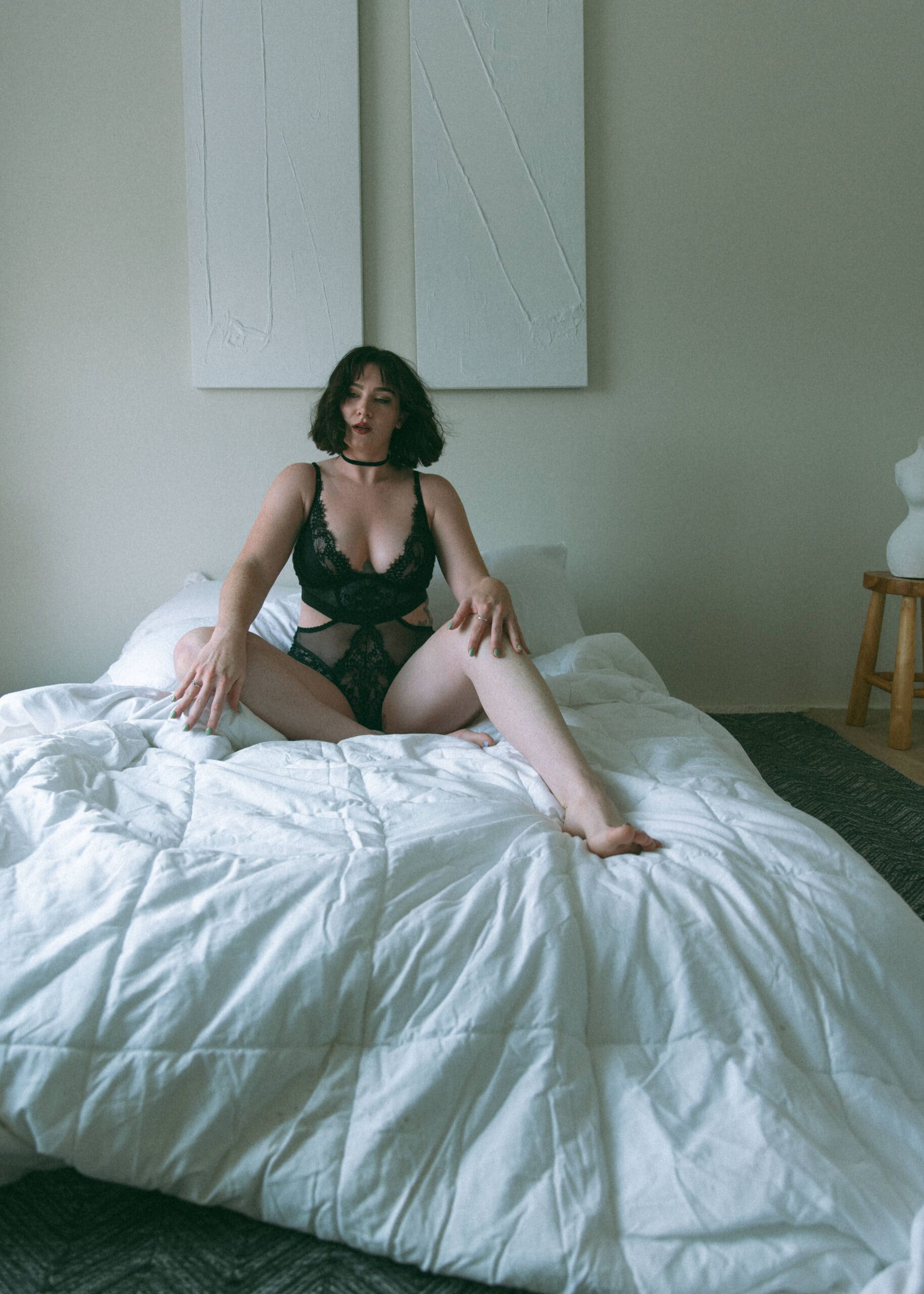 a woman sitting on a bed looking at the camera during a boudoir shoot 