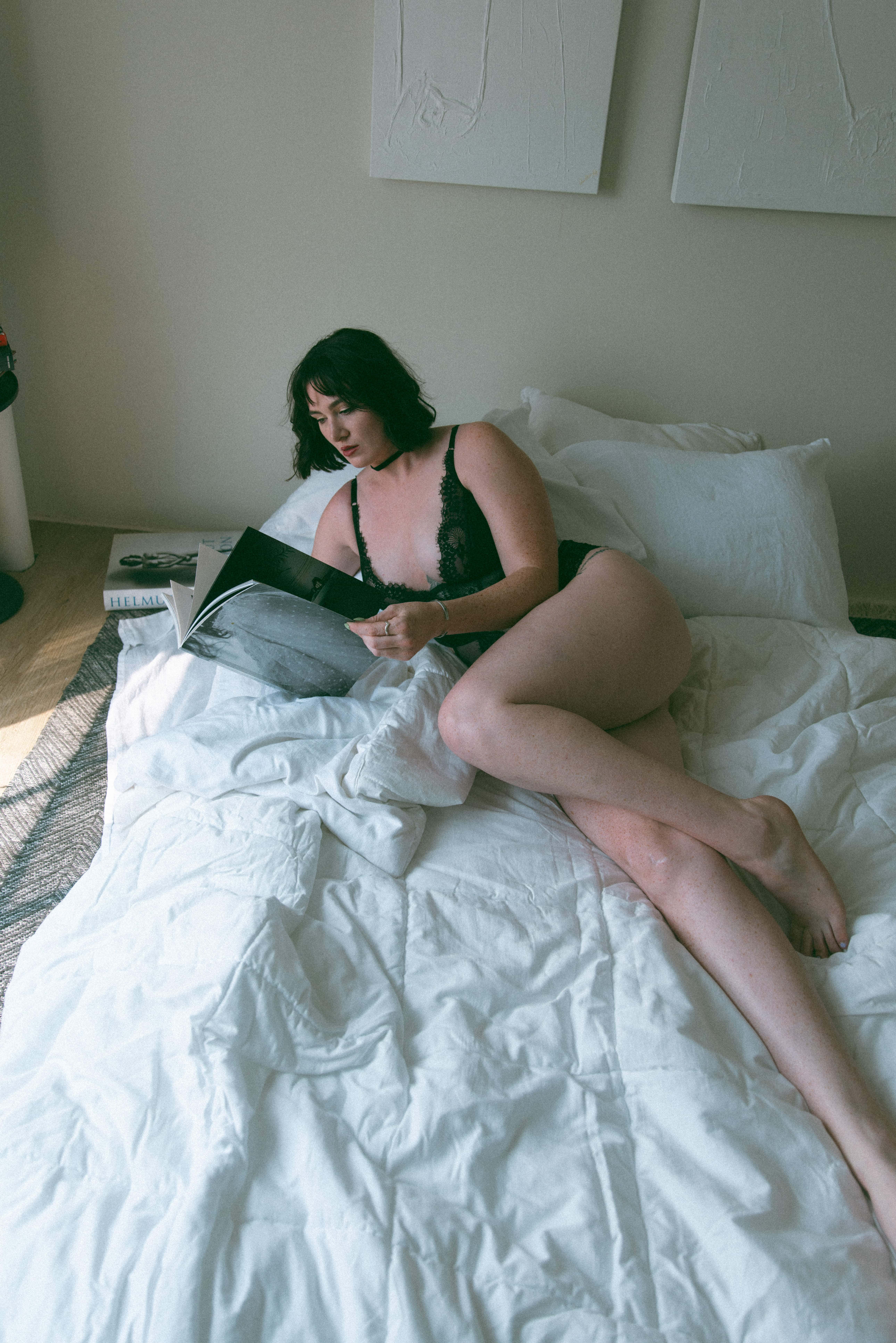 a woman in intimates laying on a bed reading a book captured by a Maryland boudoir photographer