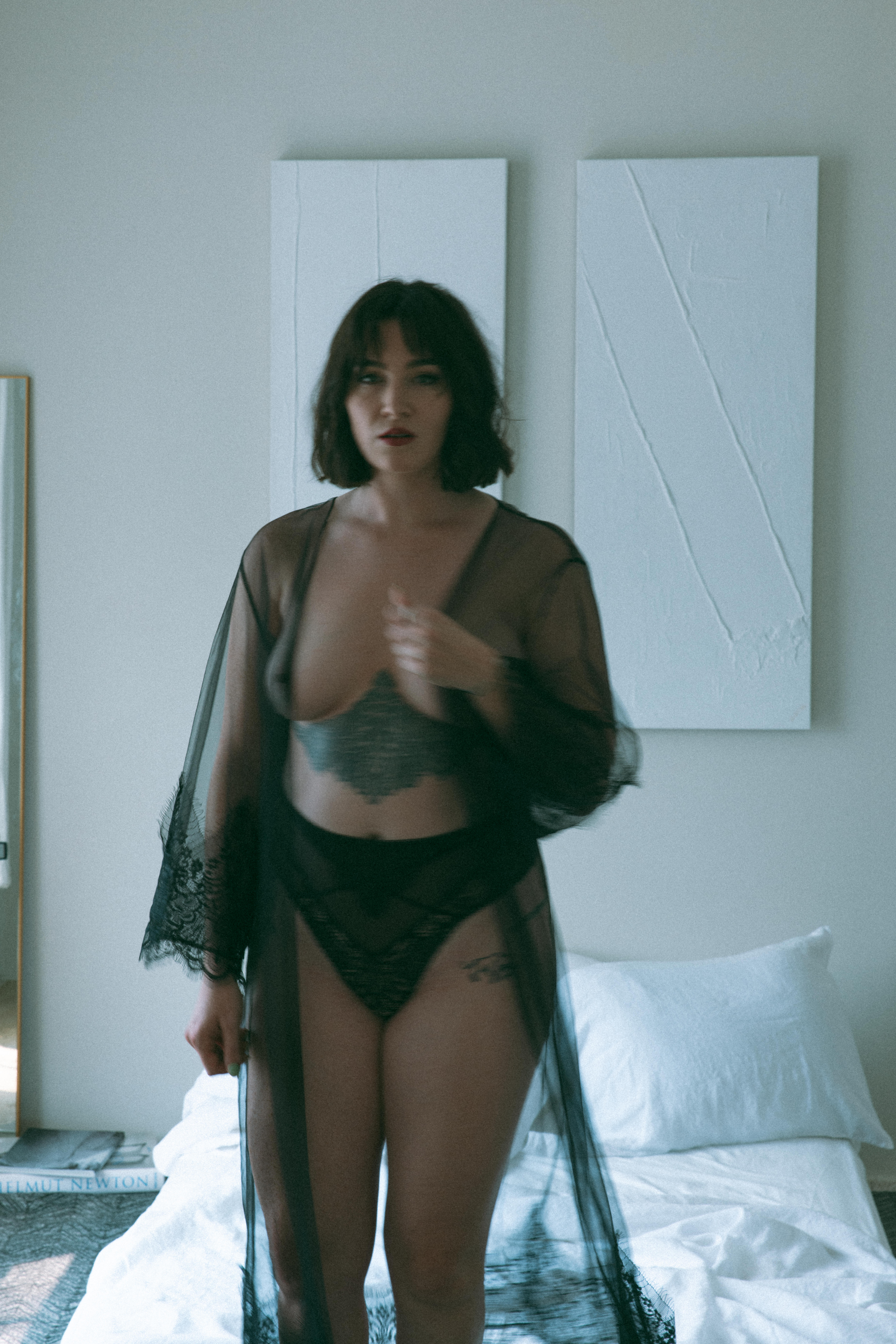a topless woman with a sheer robe standing next to a bed captured by a Maryland boudoir photographer