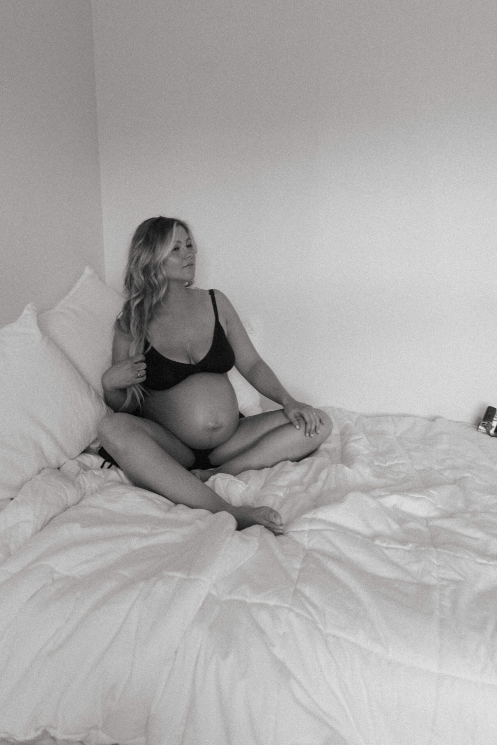 pregnant woman sitting on a bed during a boudoir pregnancy shoot