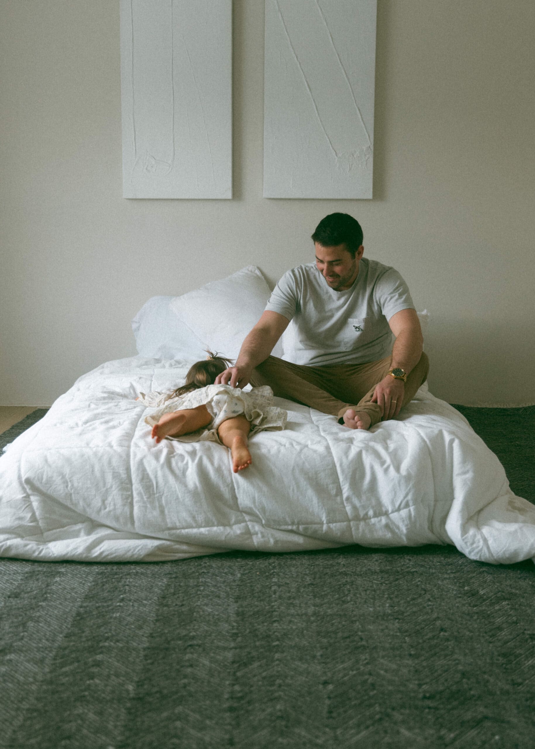dad and toddler on a bed during a studio maternity photoshoot