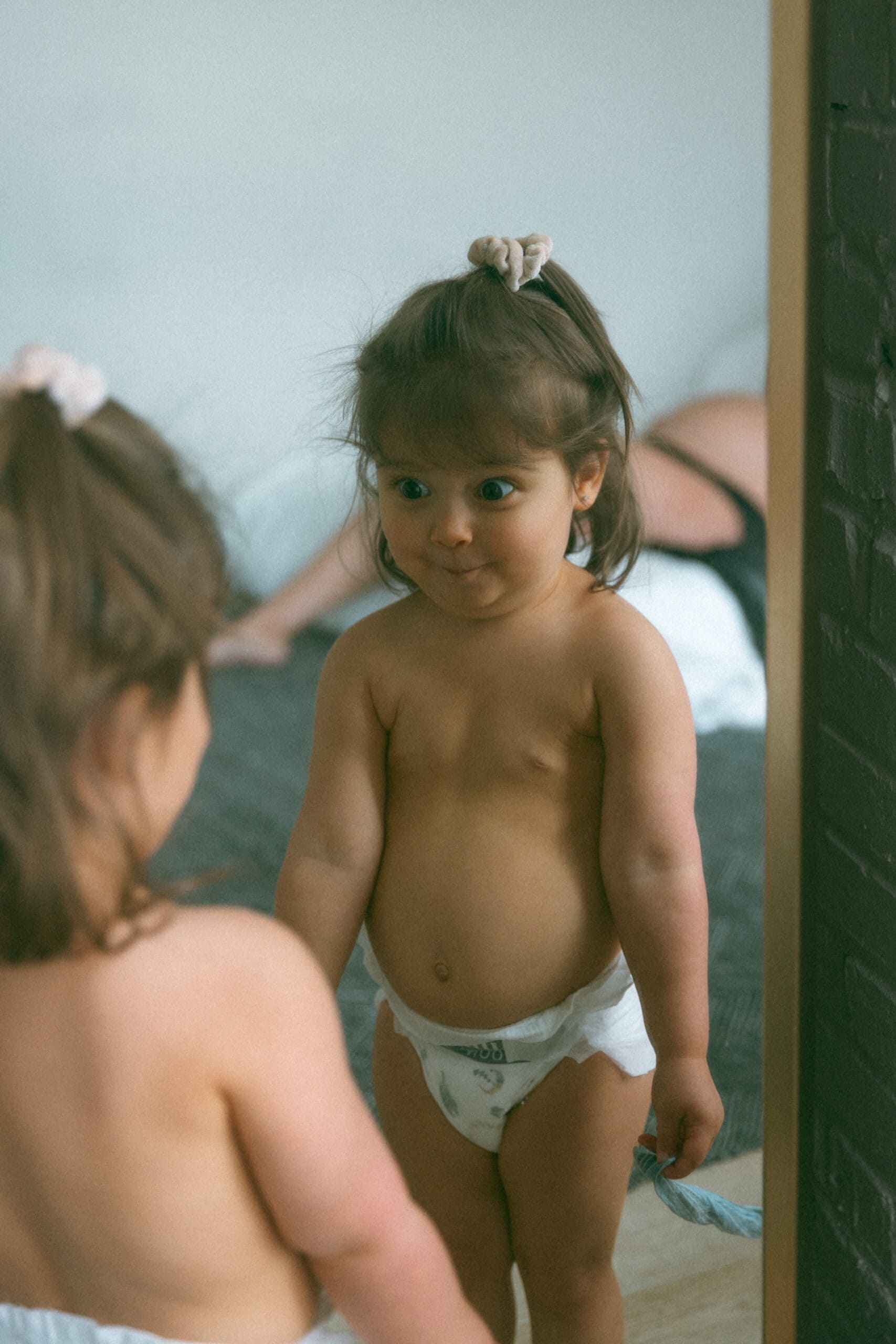 toddler making a funny face in the mirror during a studio family maternity photoshoot