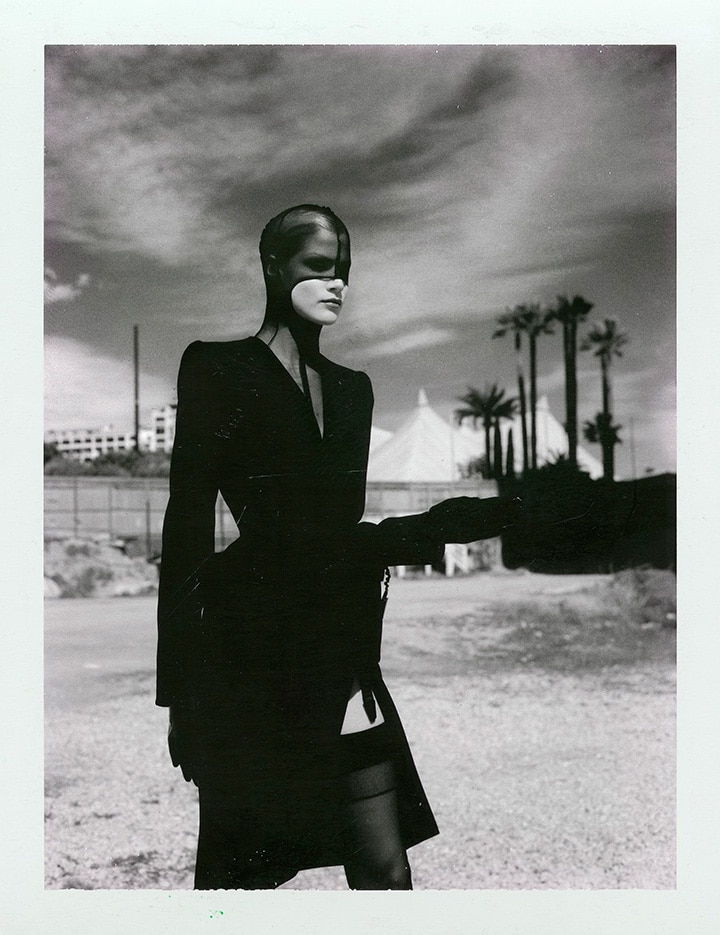 a female photoshoot by helmut newton, she is outside dressed in all black