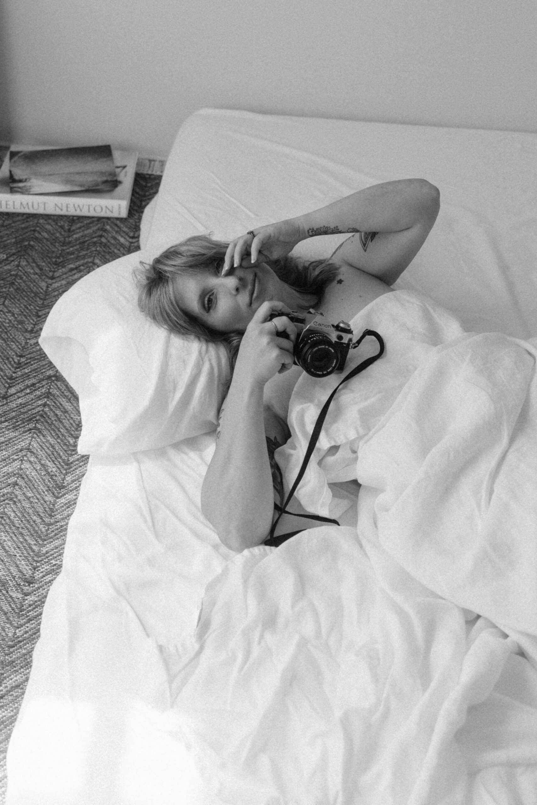 a woman laying in a bed holding a camera