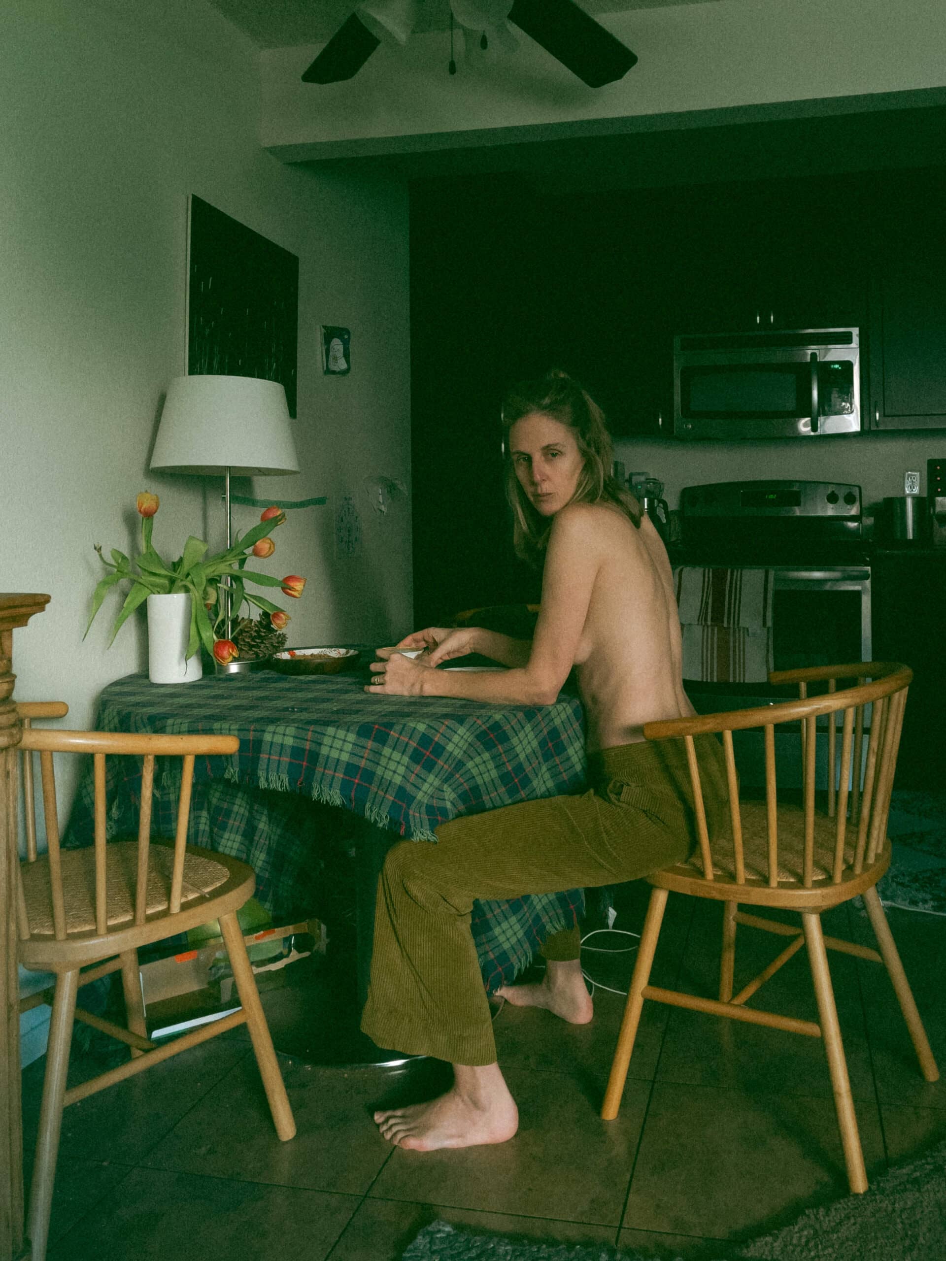 a topless woman sitting at a table 