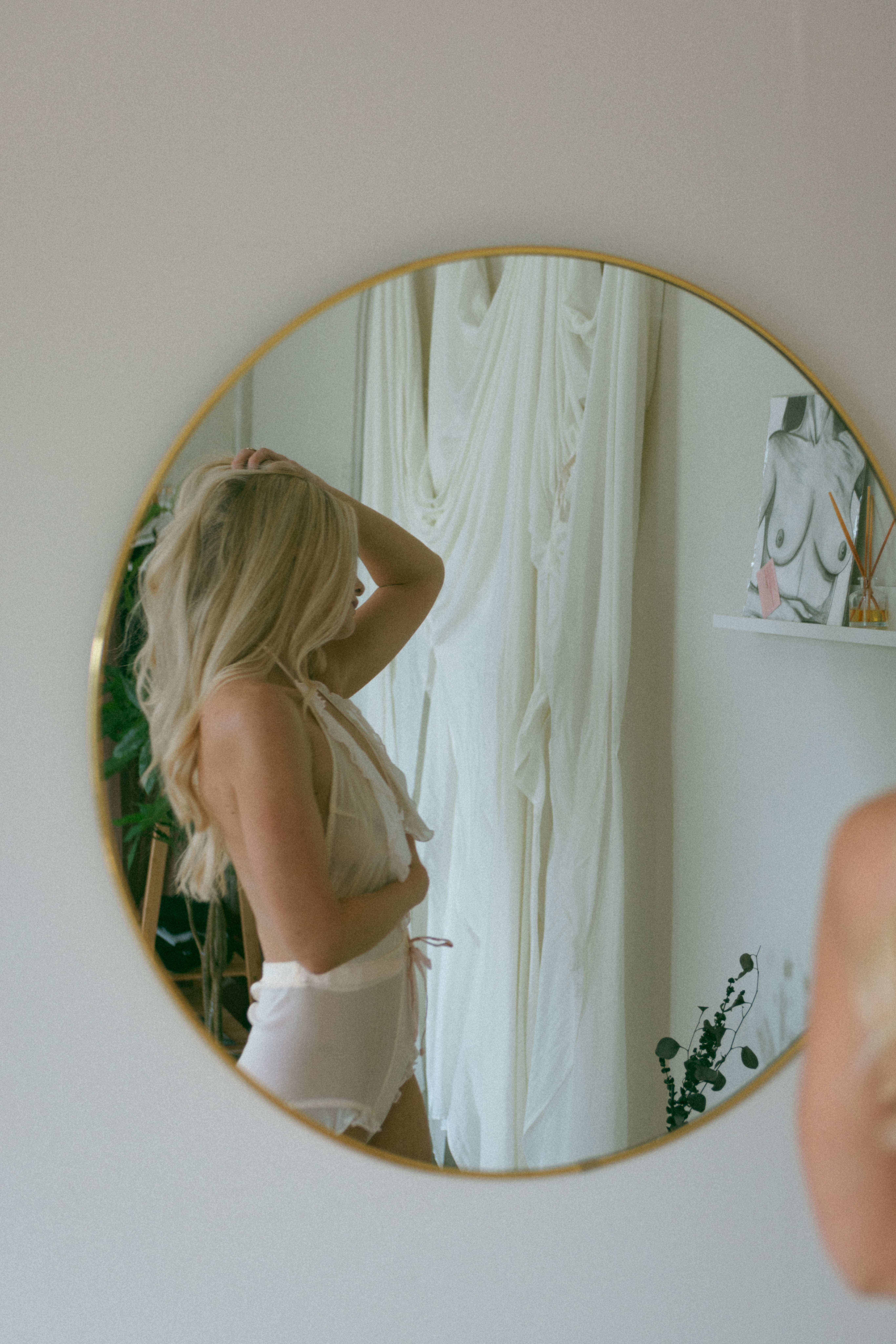 a woman through a mirror during a boho boudoir shoot