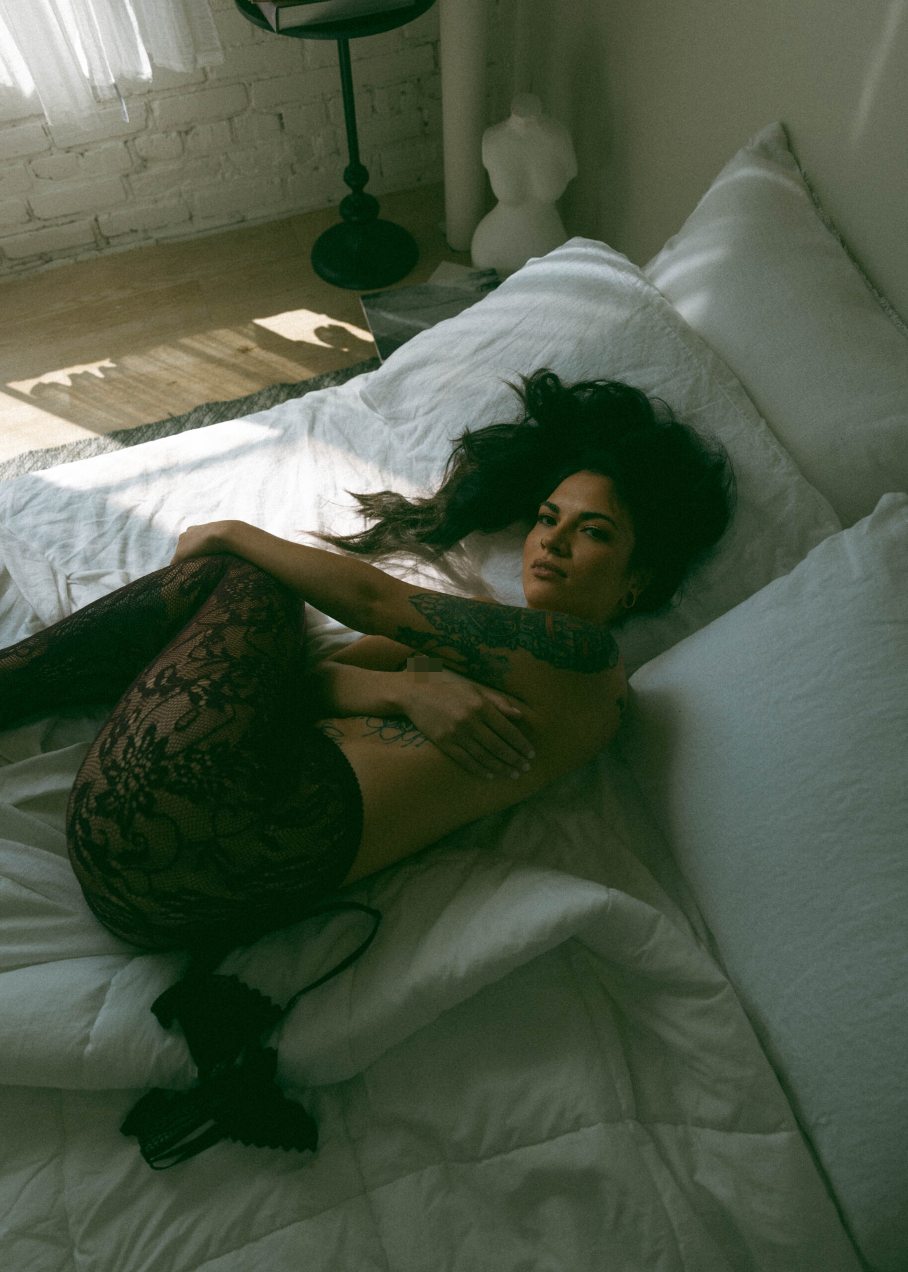 a topless woman laying in a bed for an intimate portrait 