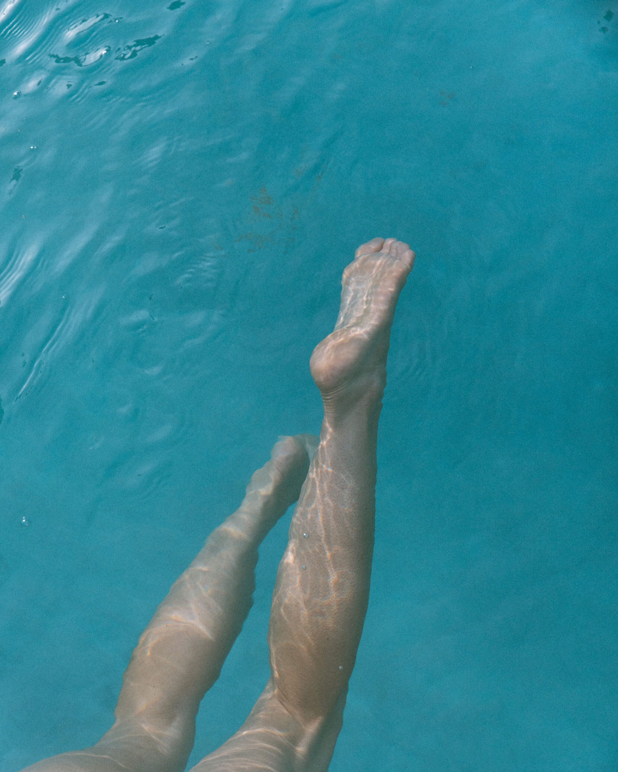 artistic female portrait photography of feet swimming in the water 
