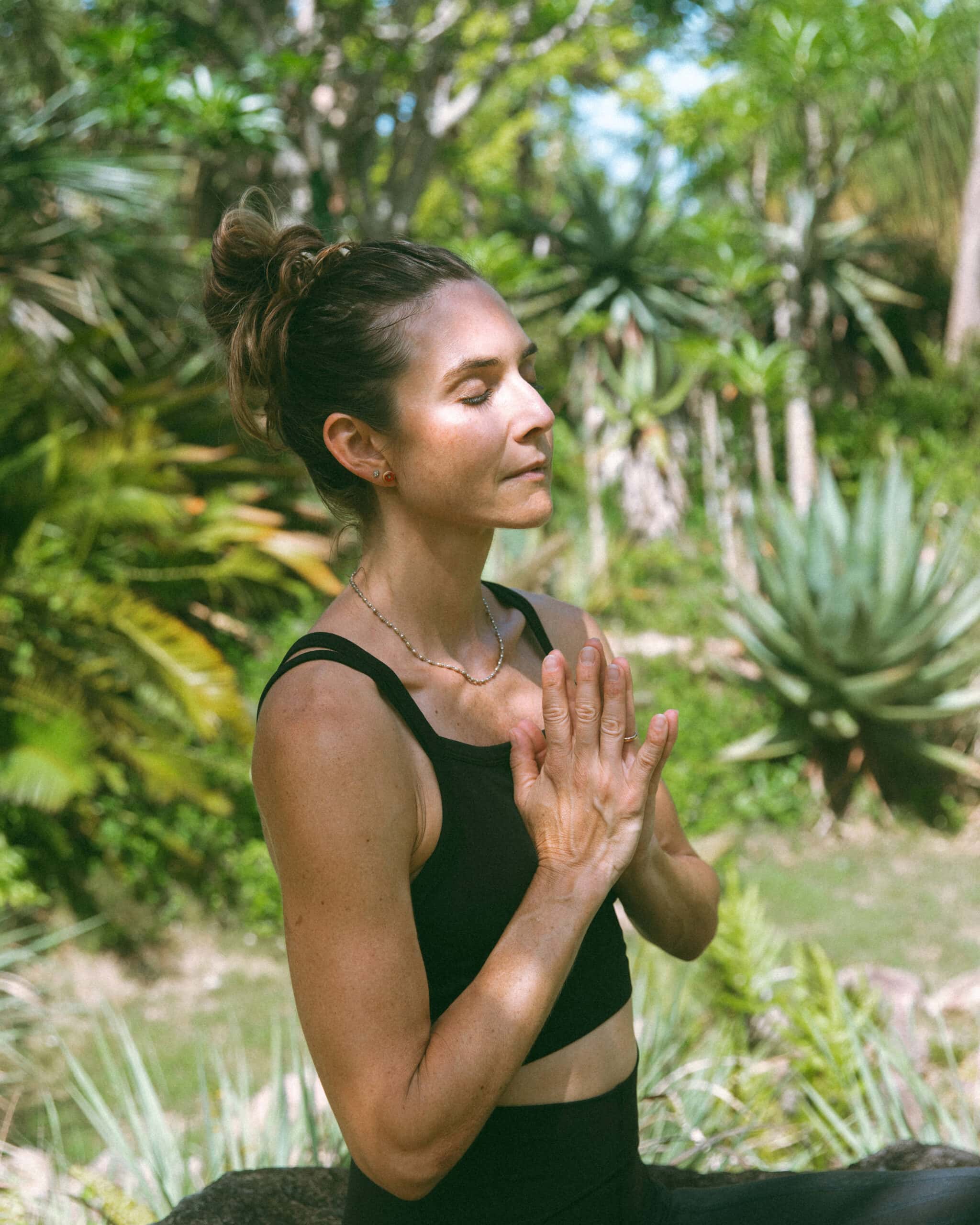 a woman with her hands in prayer pose in the jungle 