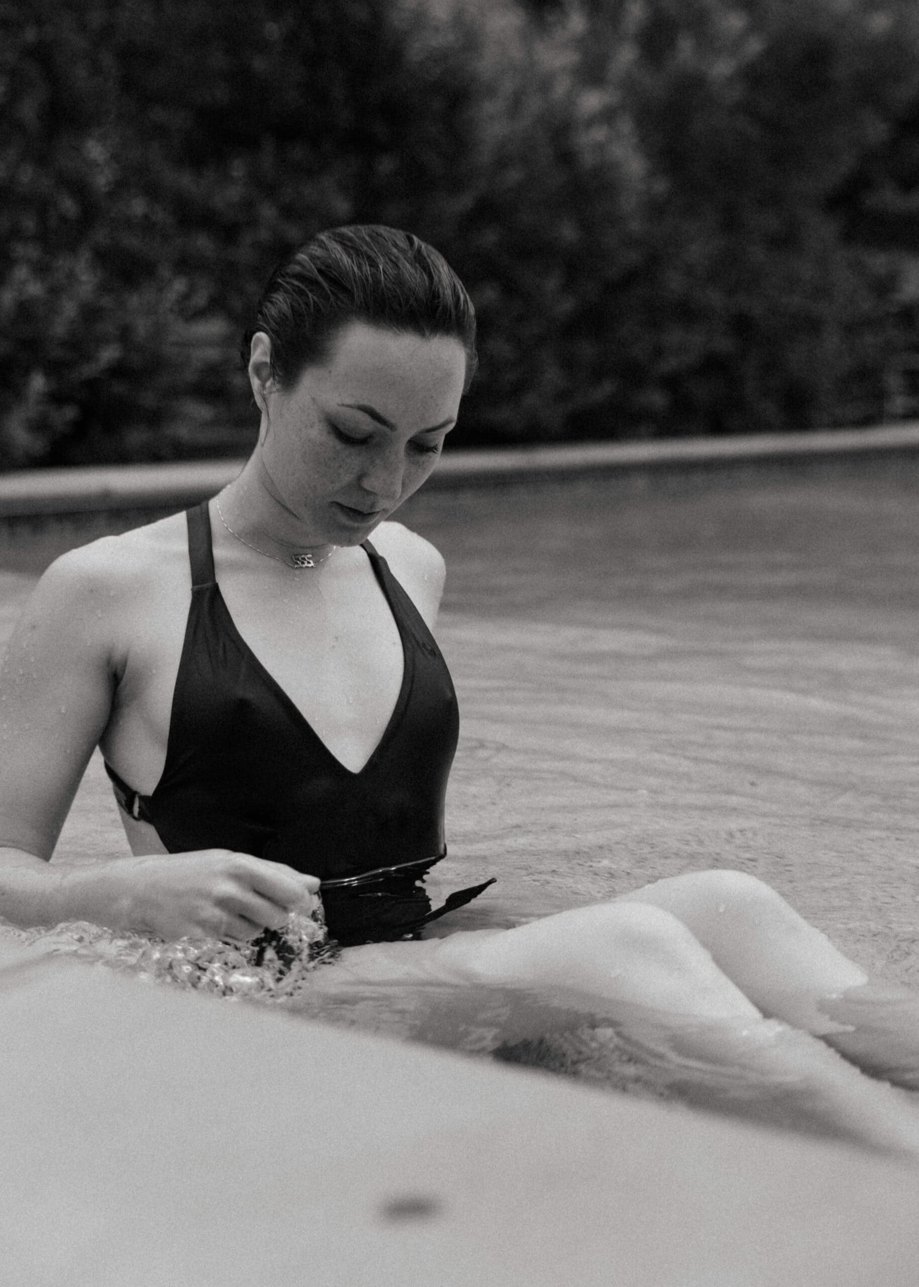 a woman adjusting her swim suit during an outdoor boudoir session