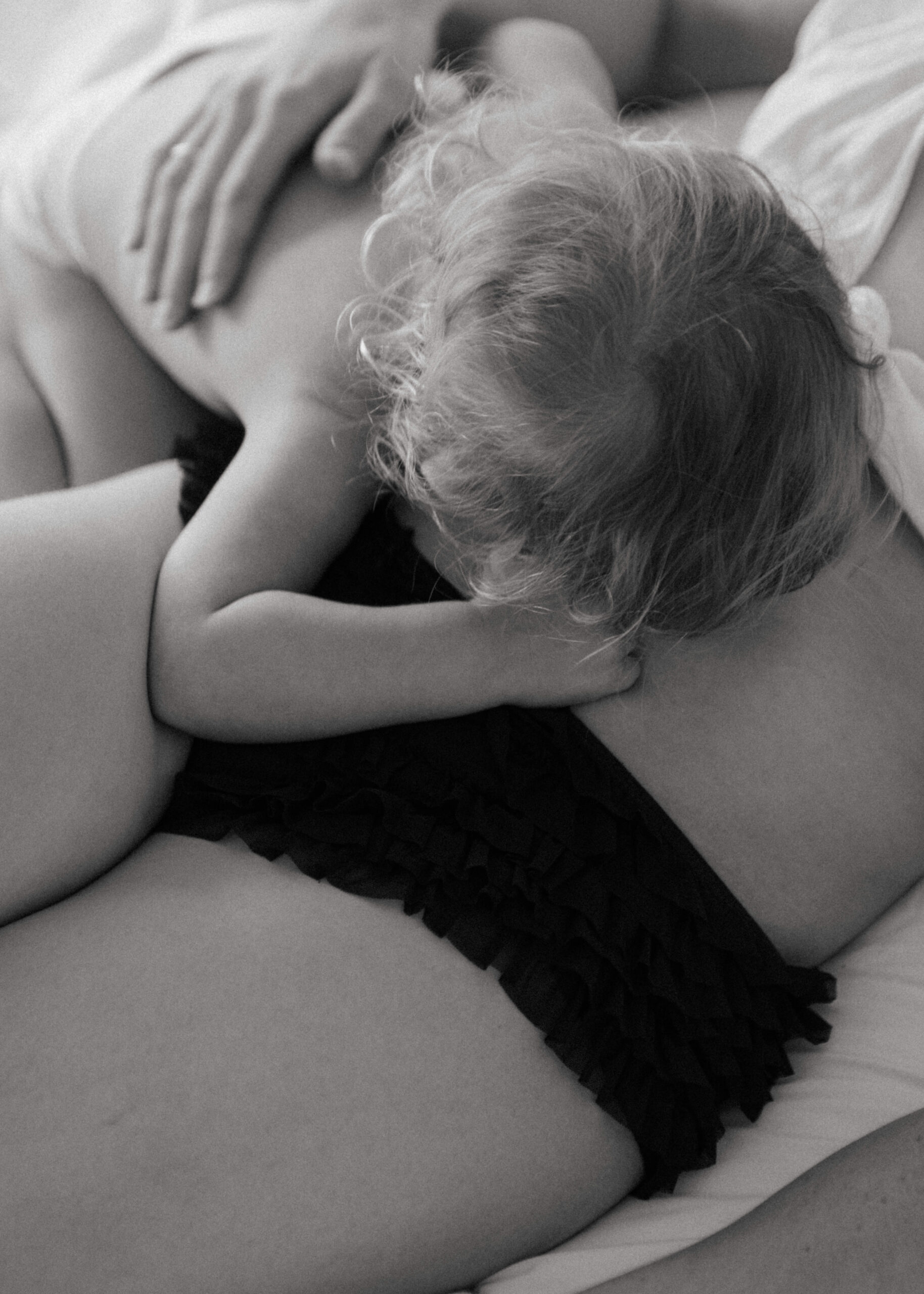baby putting her head on mother's stomach during breastfeeding photography session