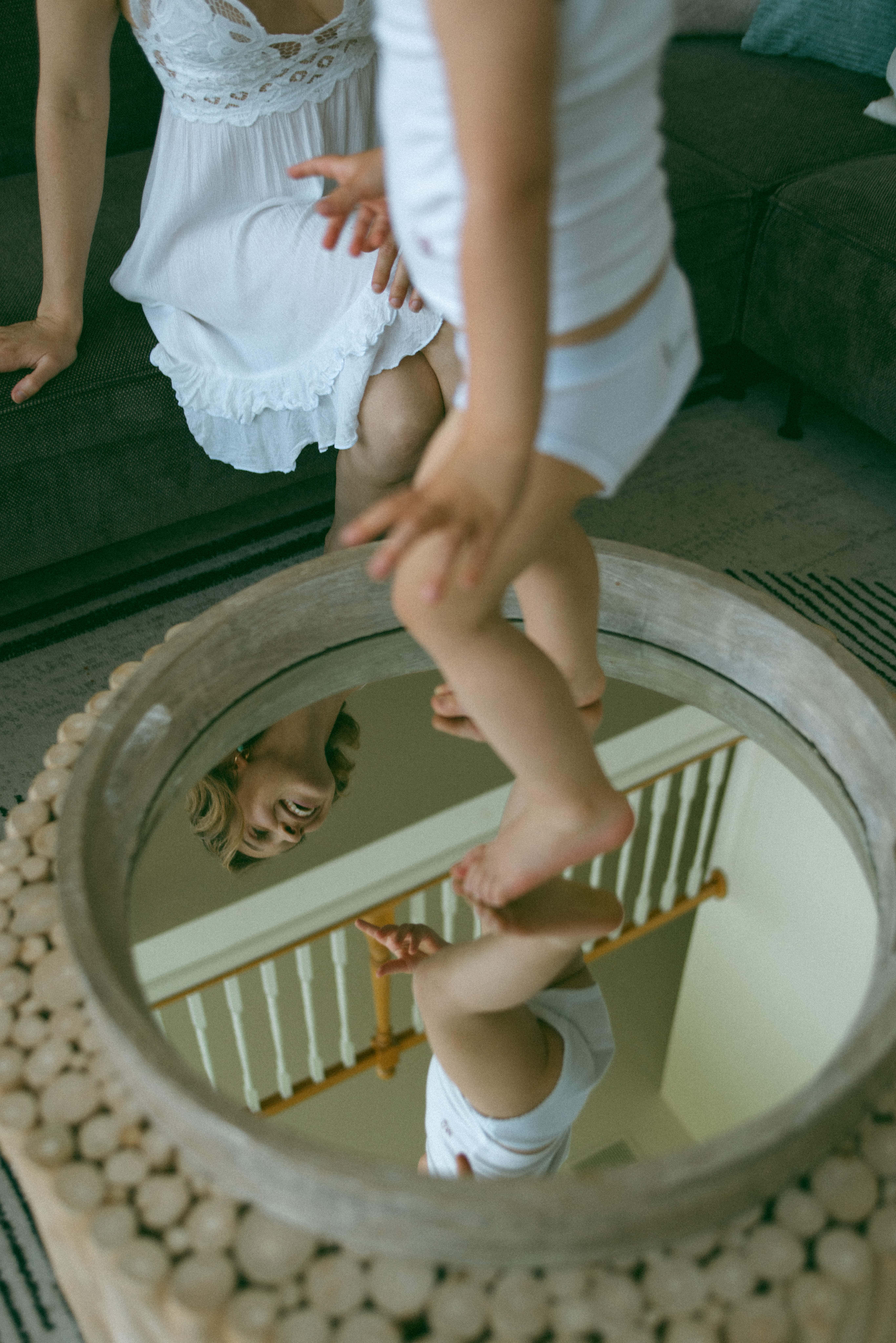 baby standing on a mirror with mother in the reflection 