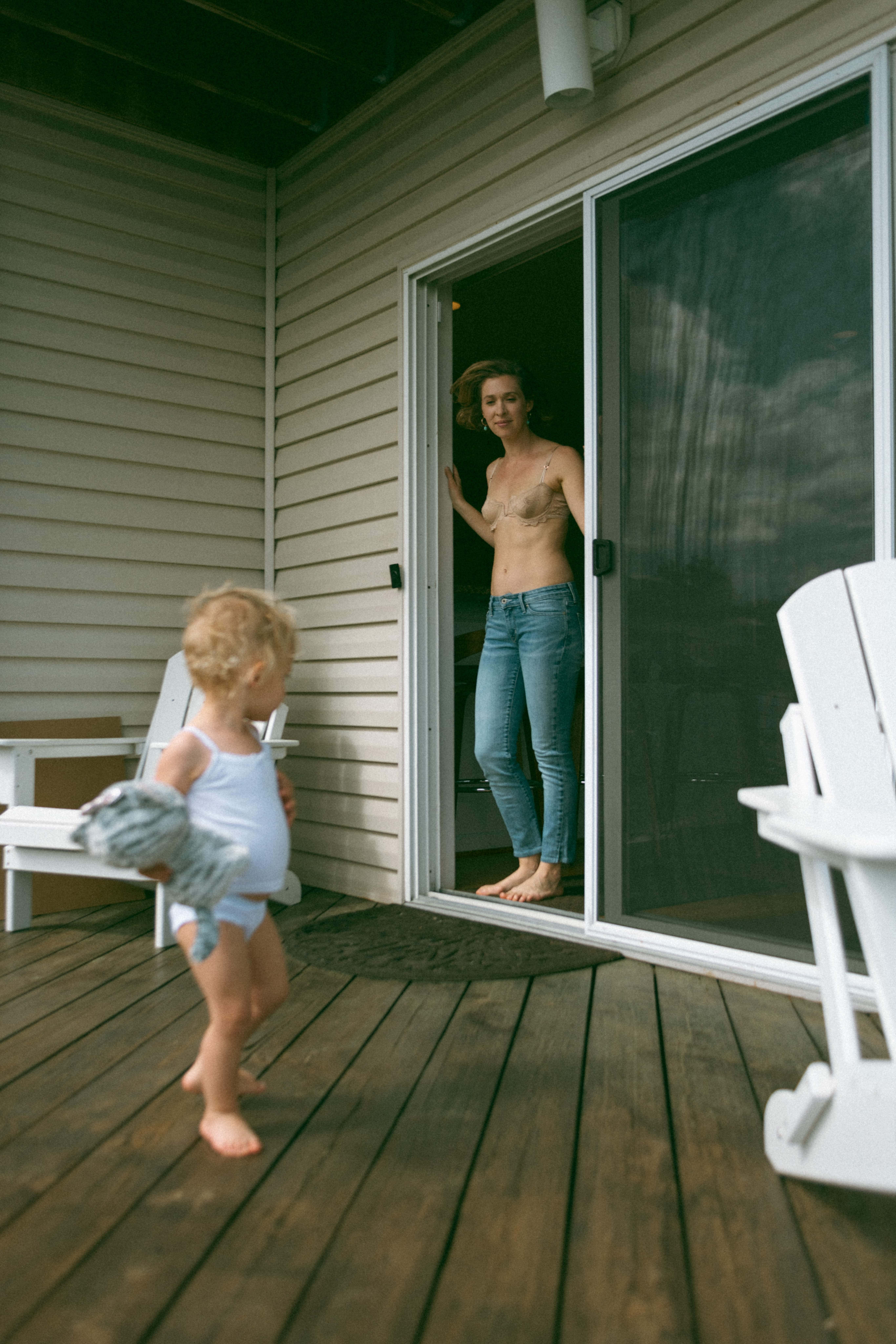 mother standing at the door while baby walks on the deck