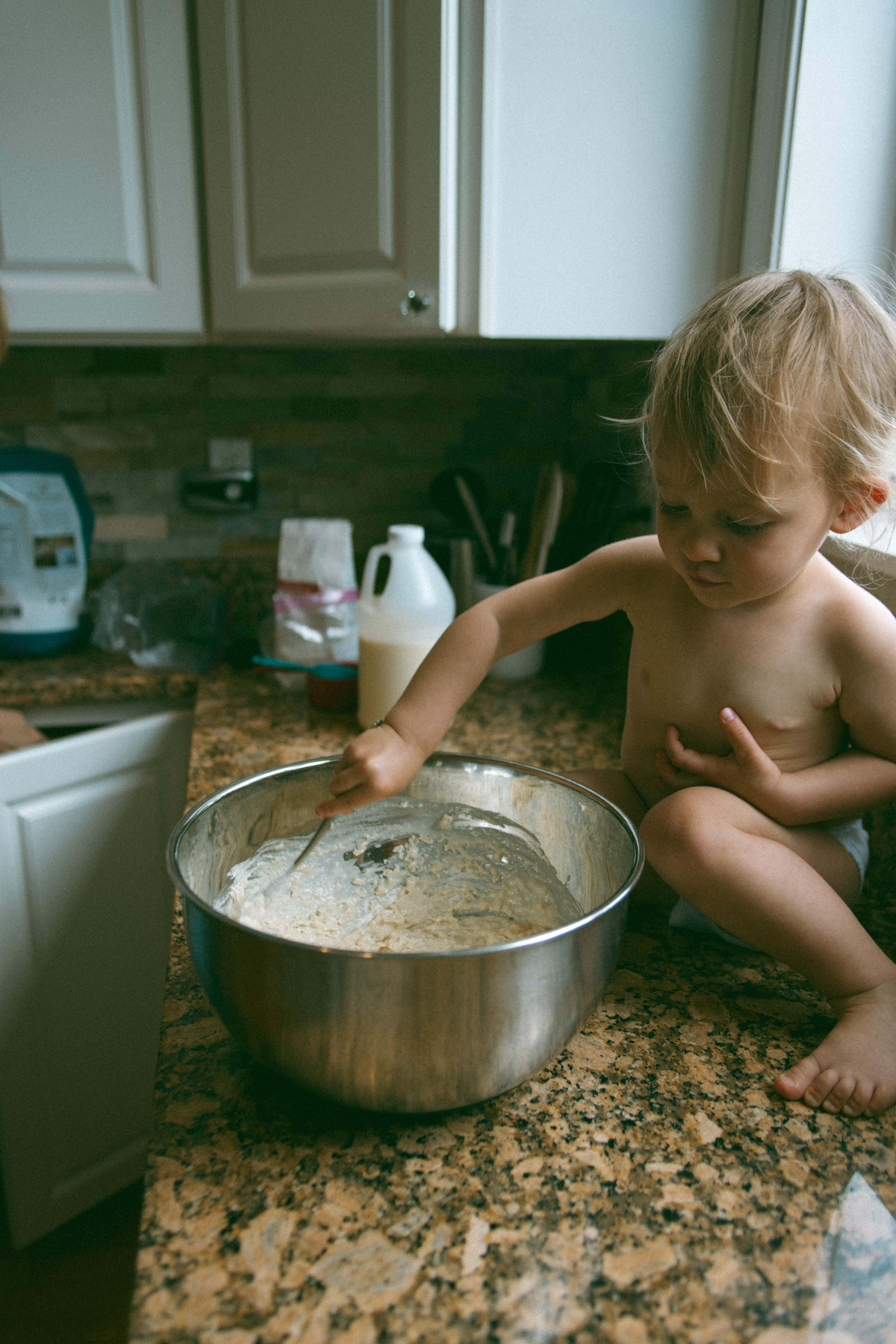 baby stirring something while sitting on the counter 
