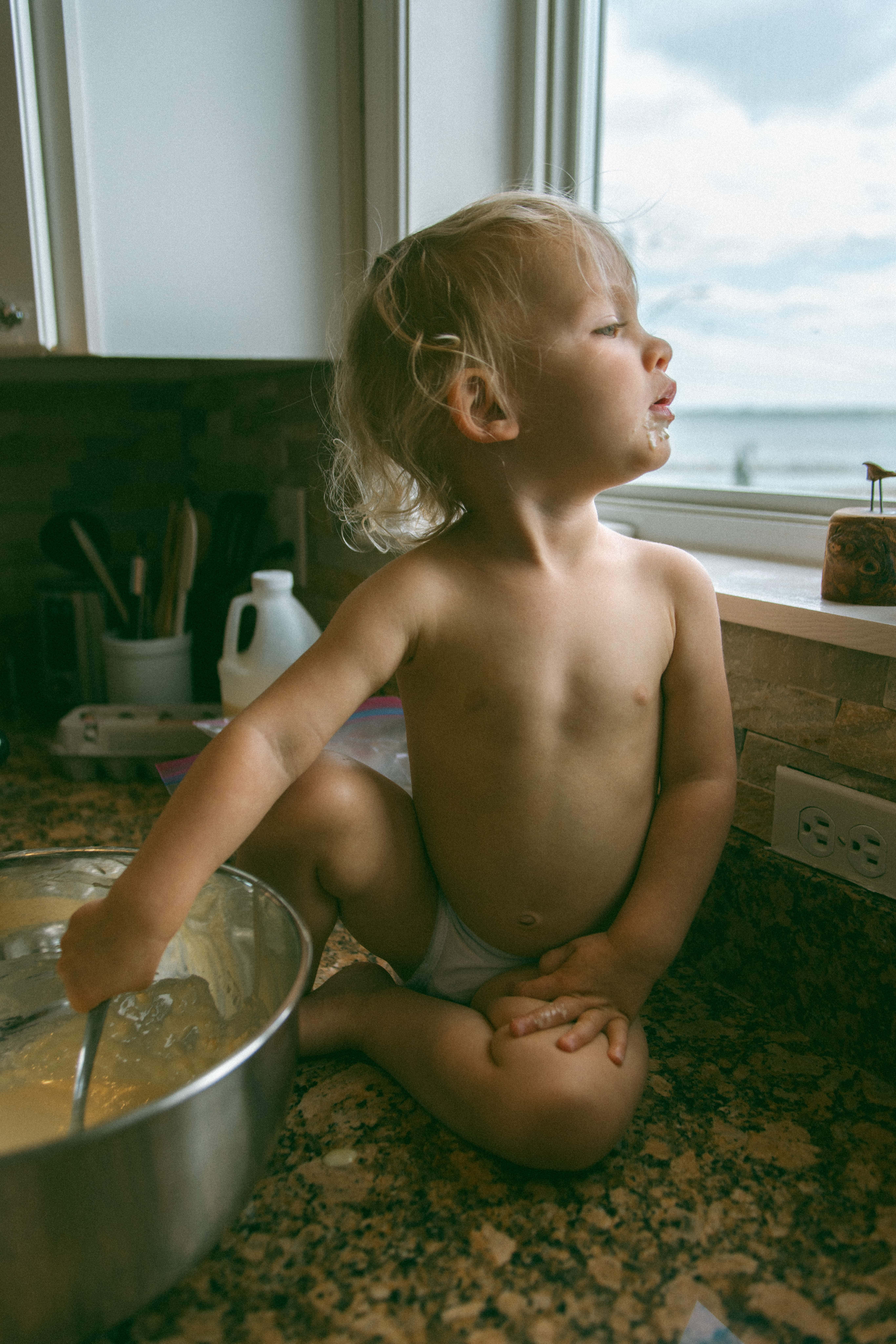 baby on the counter and looking out the window during breastfeeding photography session