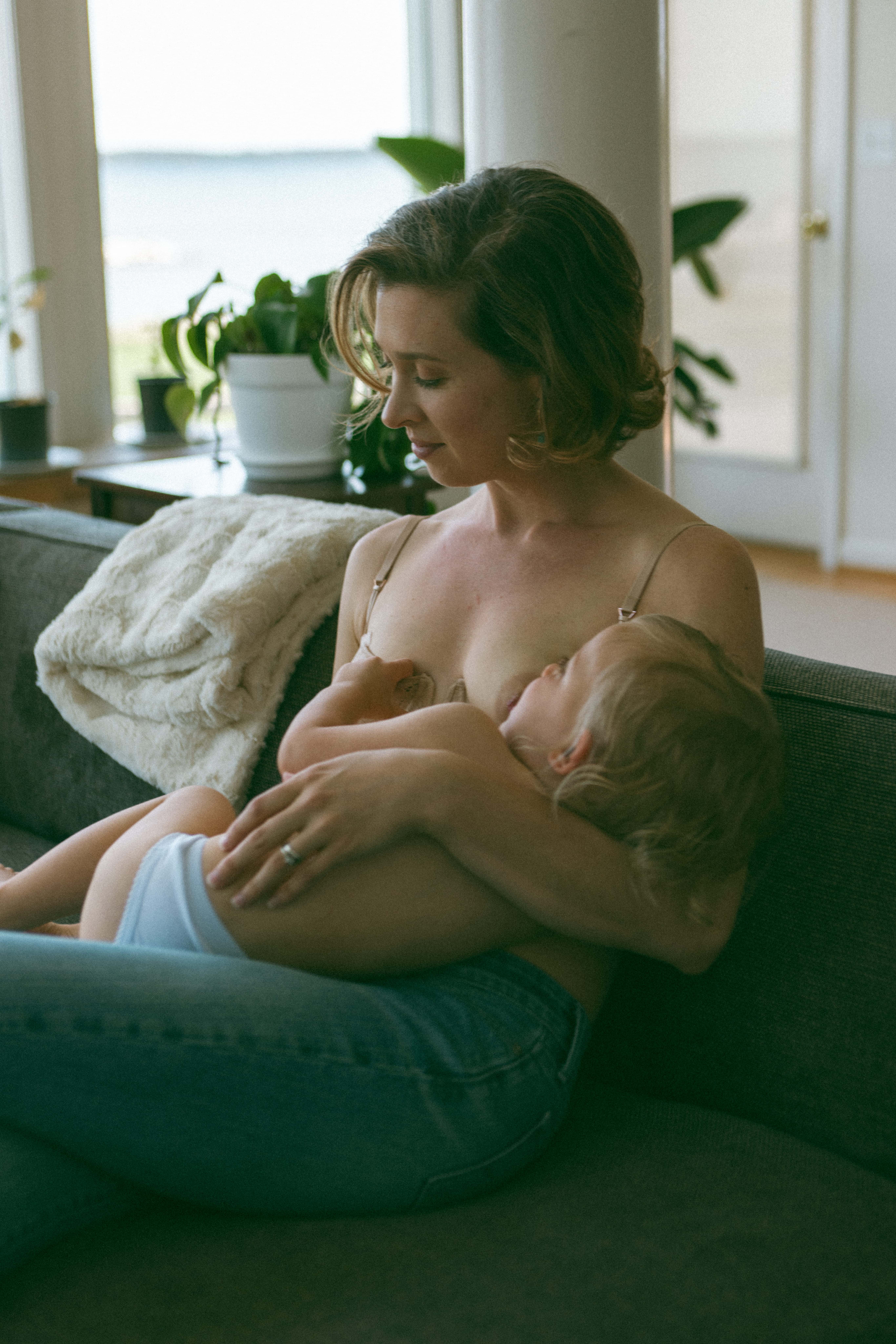 mother sitting on the couch breastfeeding 