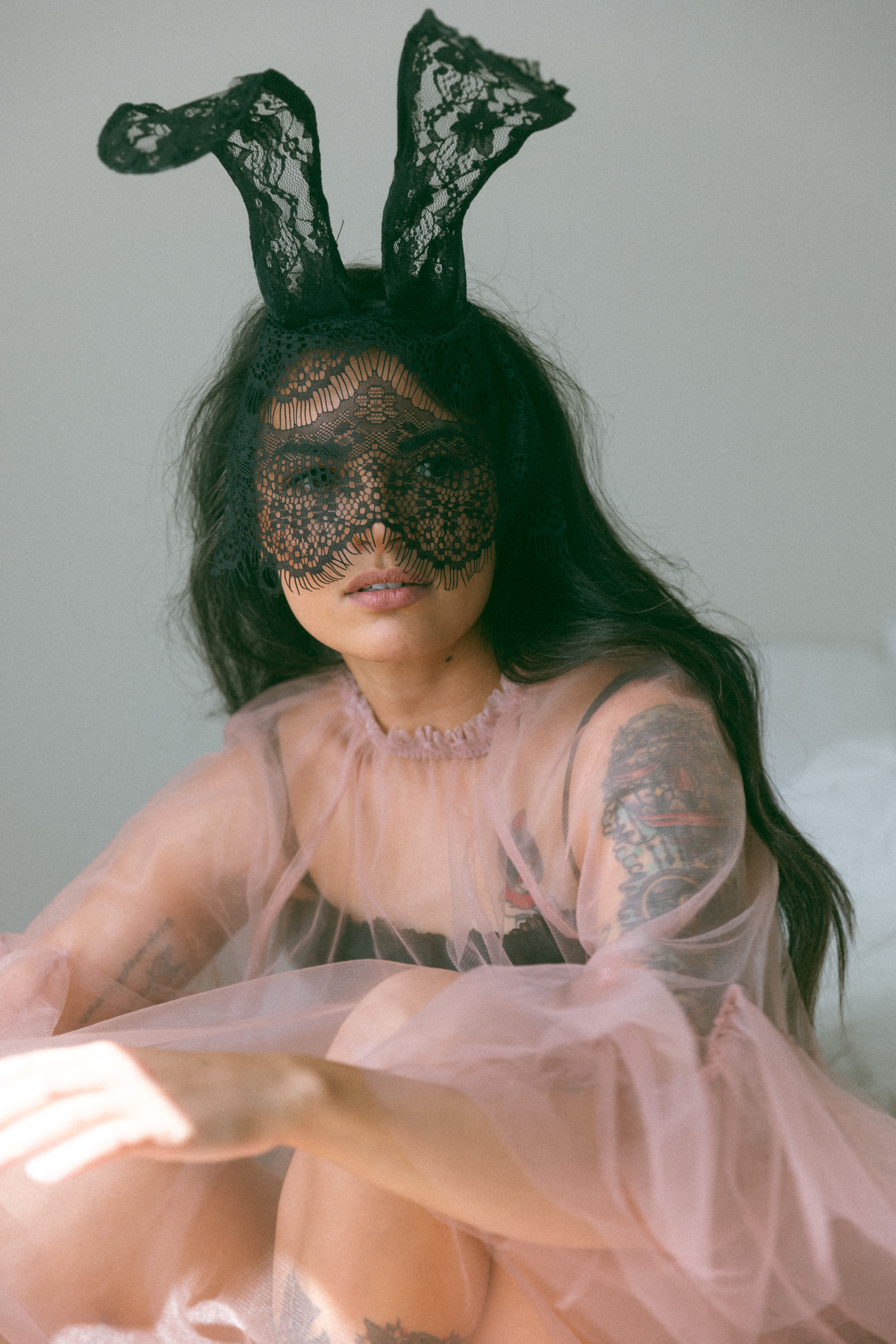a masked woman wearing a sheer outfit during a boudoir photoshoot 