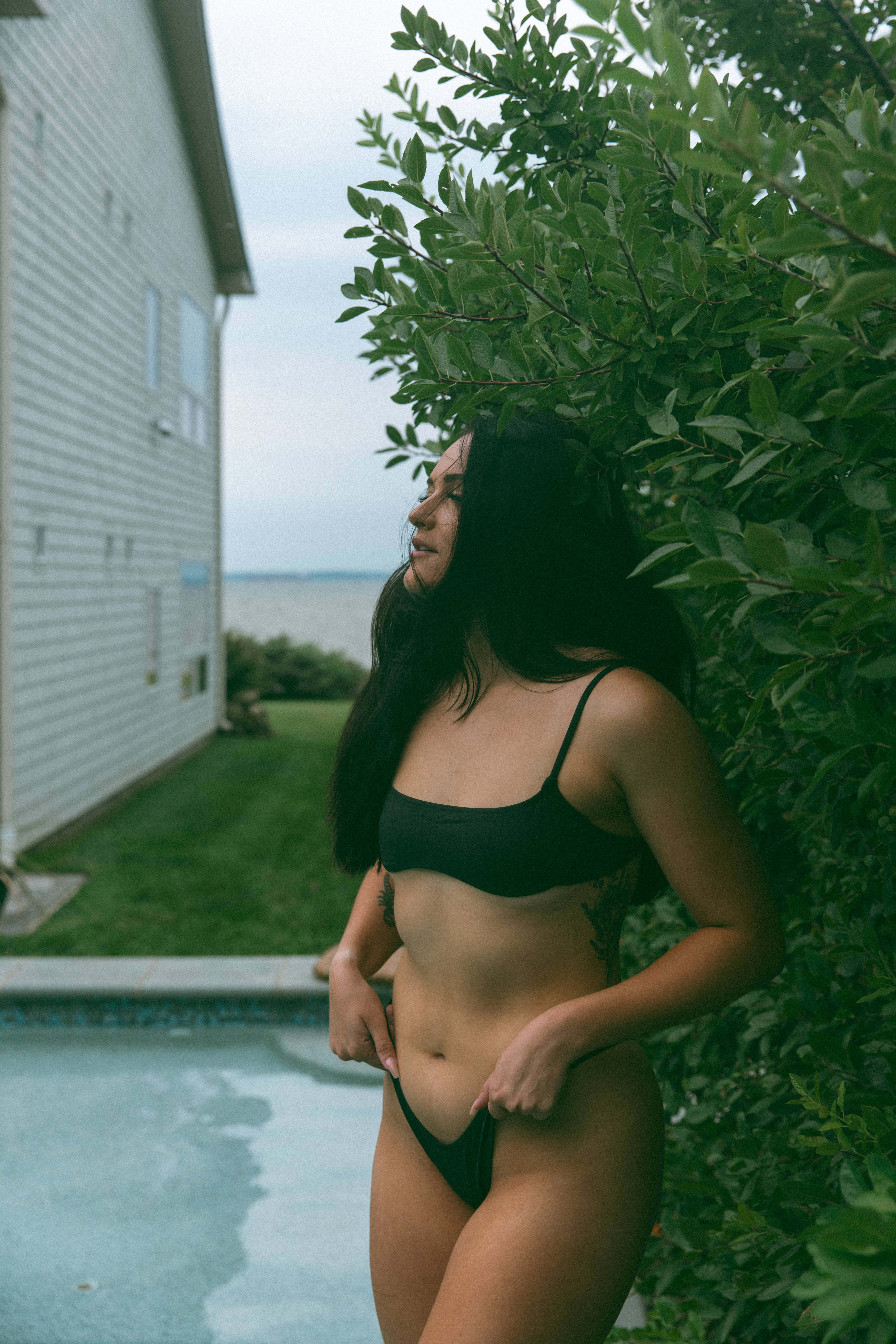 a woman in a bikini adjusting her swim bottoms 