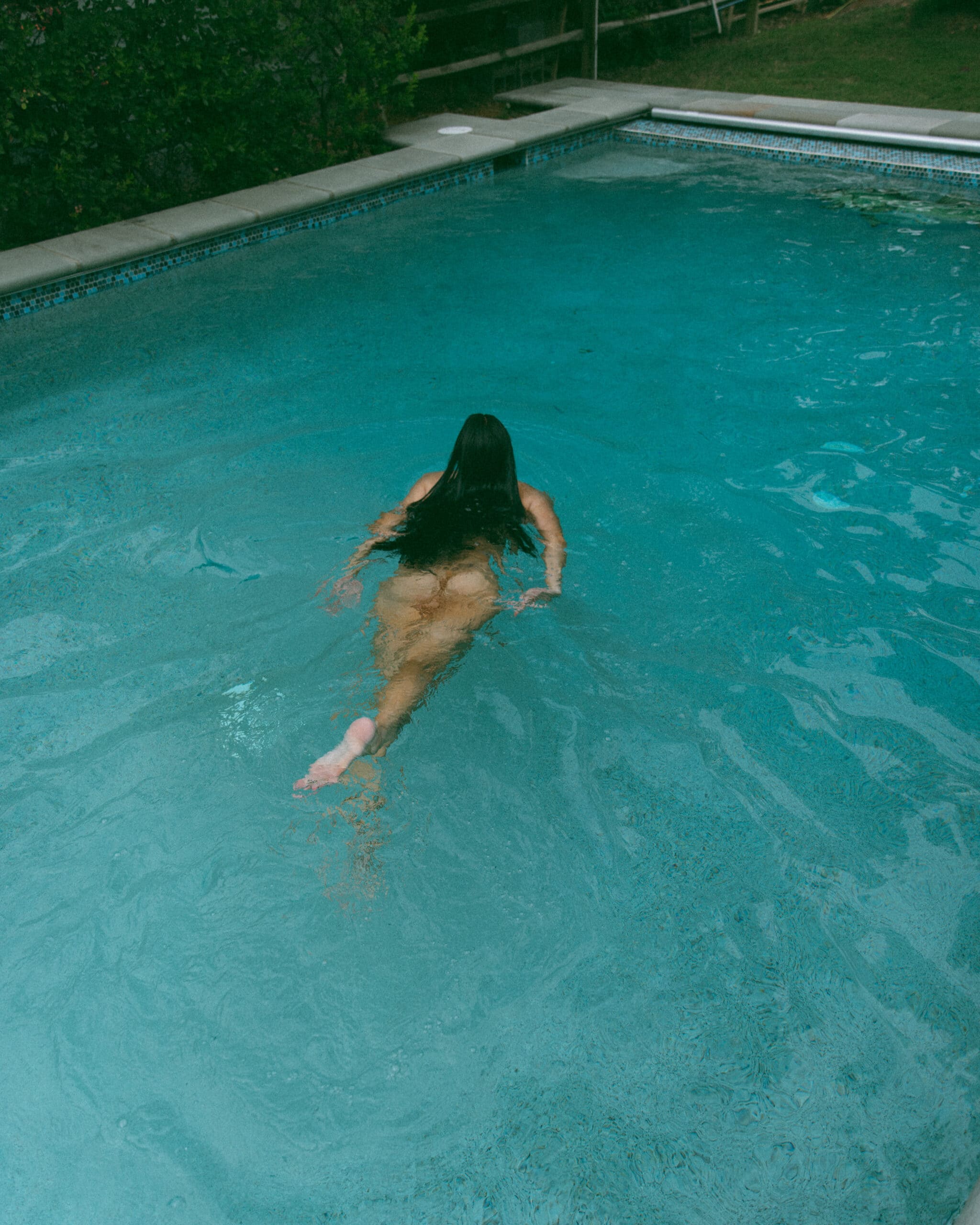 a naked woman swimming in a pool