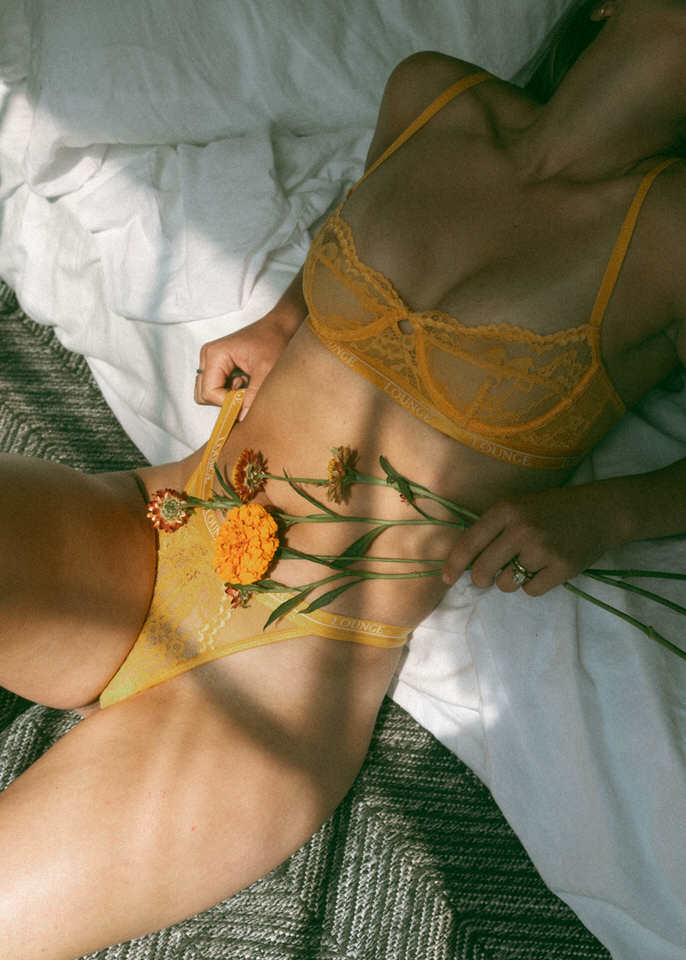 a woman wearing lingerie holding flowers over her stomach during a maryland boudoir photography session 