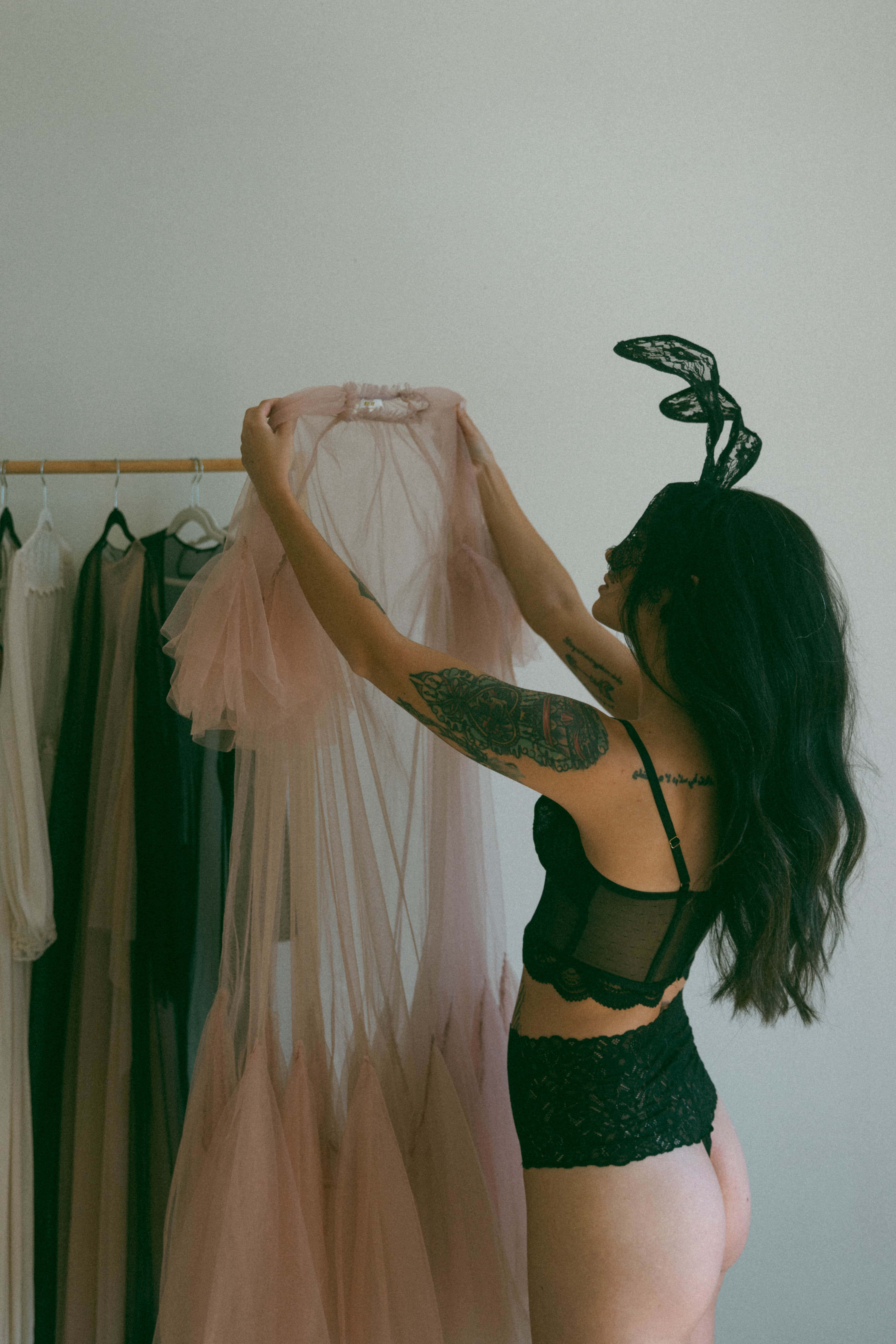 a woman holding up an outfit before she puts it on during a maryland boudoir photography session 