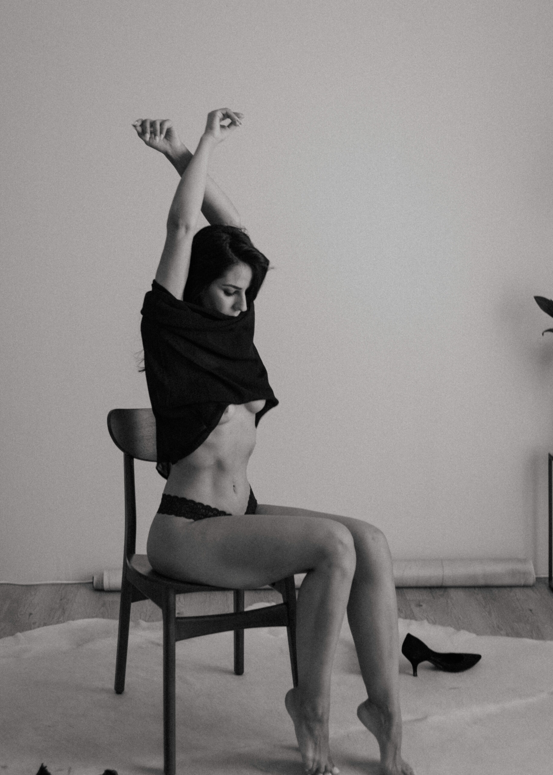 a woman sitting on a chair taking off her clothes during a maryland boudoir photography session 